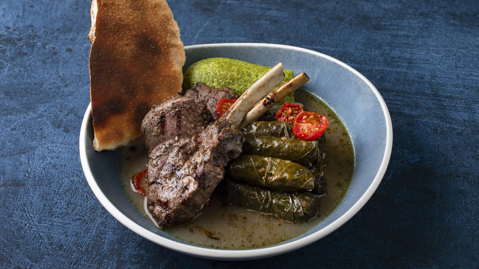 Stuffed zucchini and vine leaves filled with rice and minced lamb meat, served with lamb