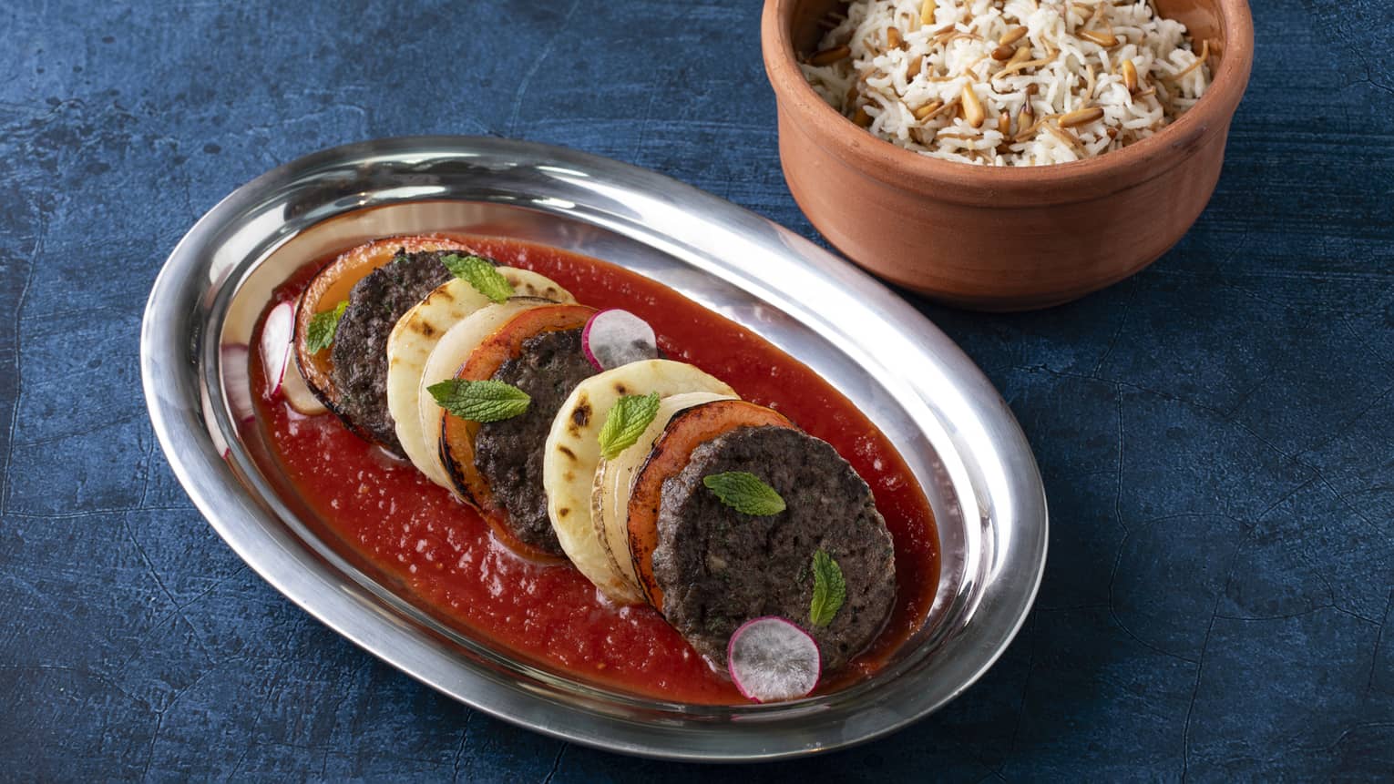 Baked Kafta layered with potatoes, tomatoes, onion, vermicelli rice and spicy tomato sauce