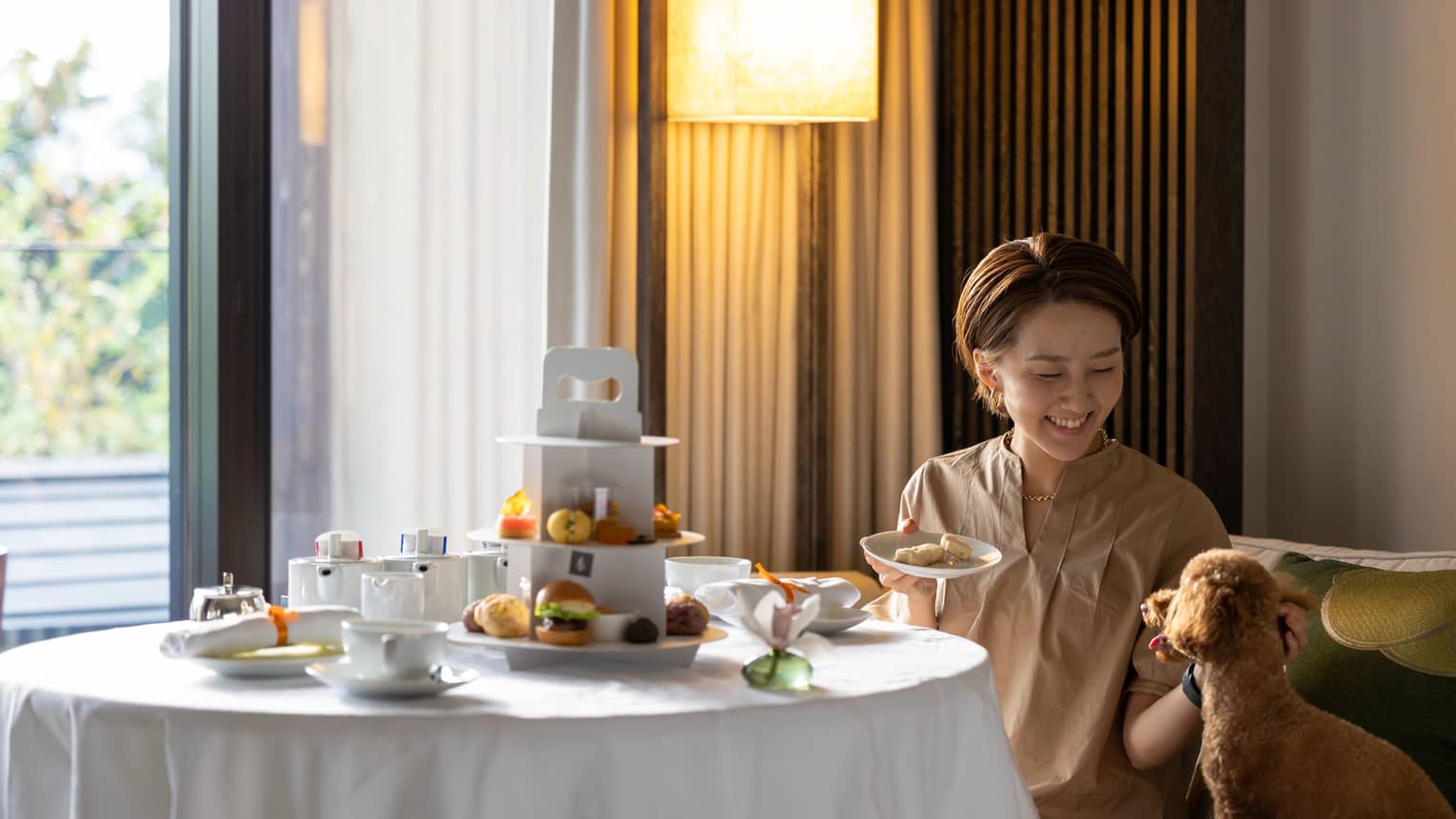 Female guest enjoys in-room dining with her toy poodle
