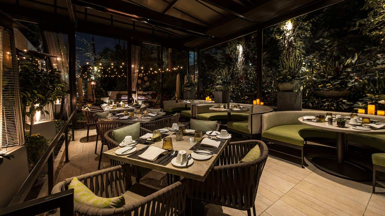 Culina Restaurant dining patio, plush green and grey dining chairs, booths under awning at night