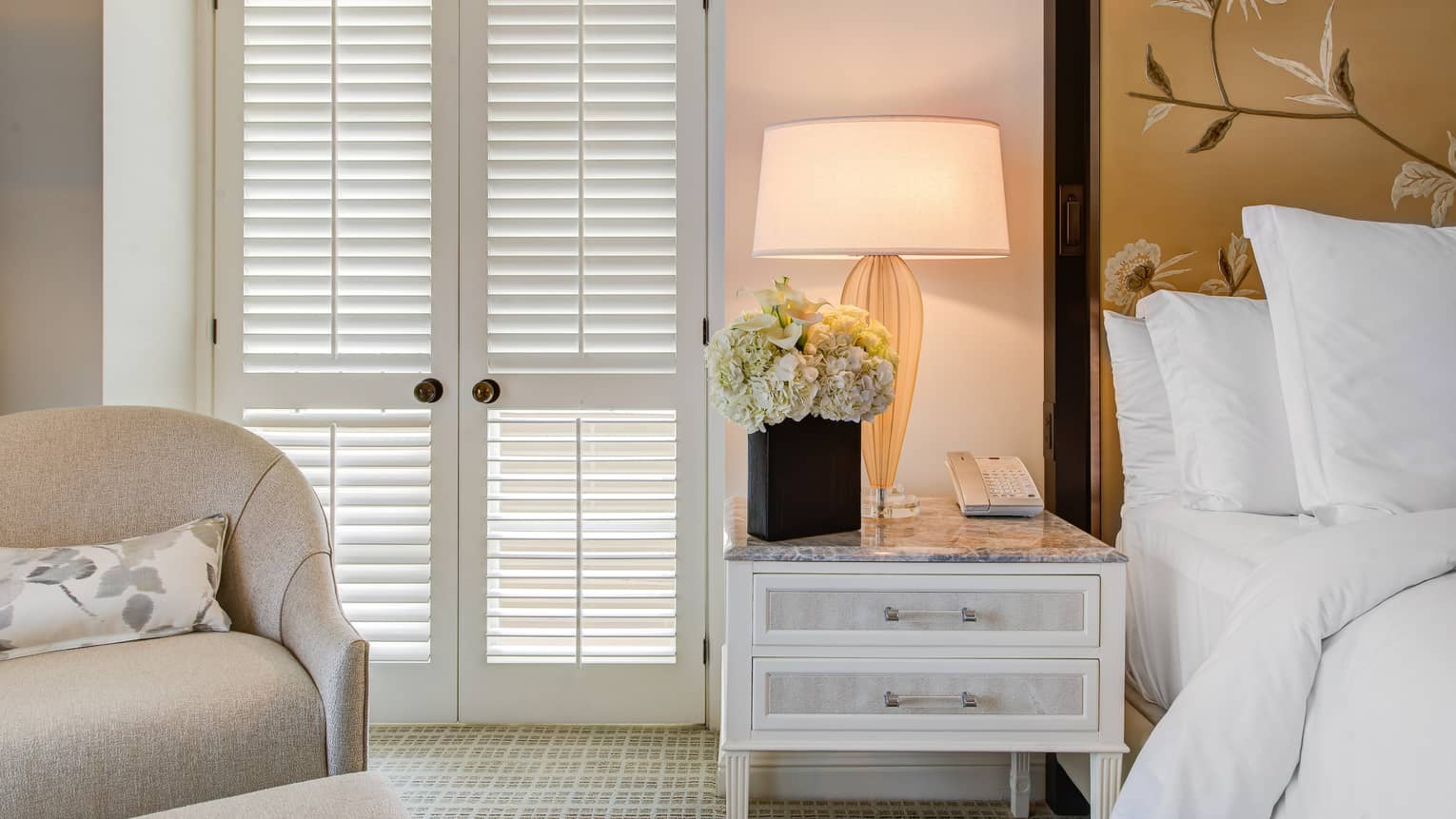 Deluxe Balcony Wellness Room white French doors, armchair, hotel bed by dresser with lamp