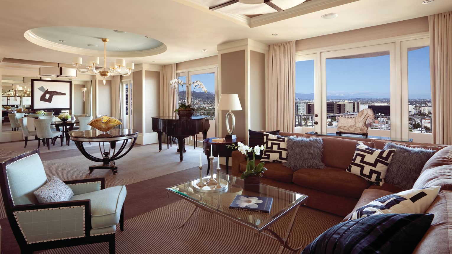 Presidential Suite East large living, dining room under soaring ceiling, picture windows with views of city, hills