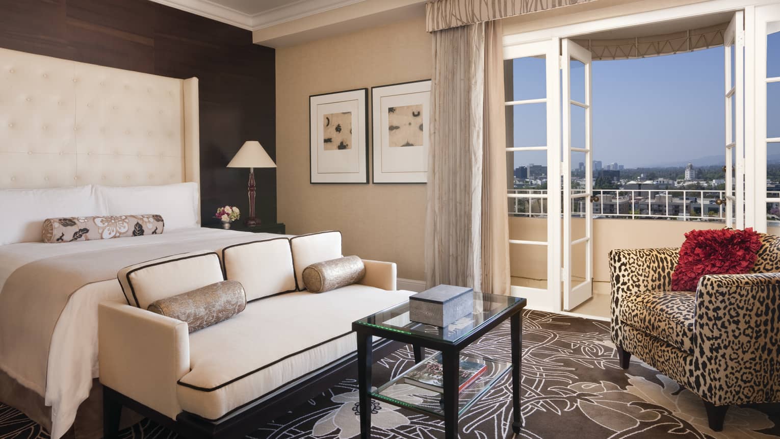 Royal Suite white loveseat, glass table at foot of bed with white headboard, leopard print armchair