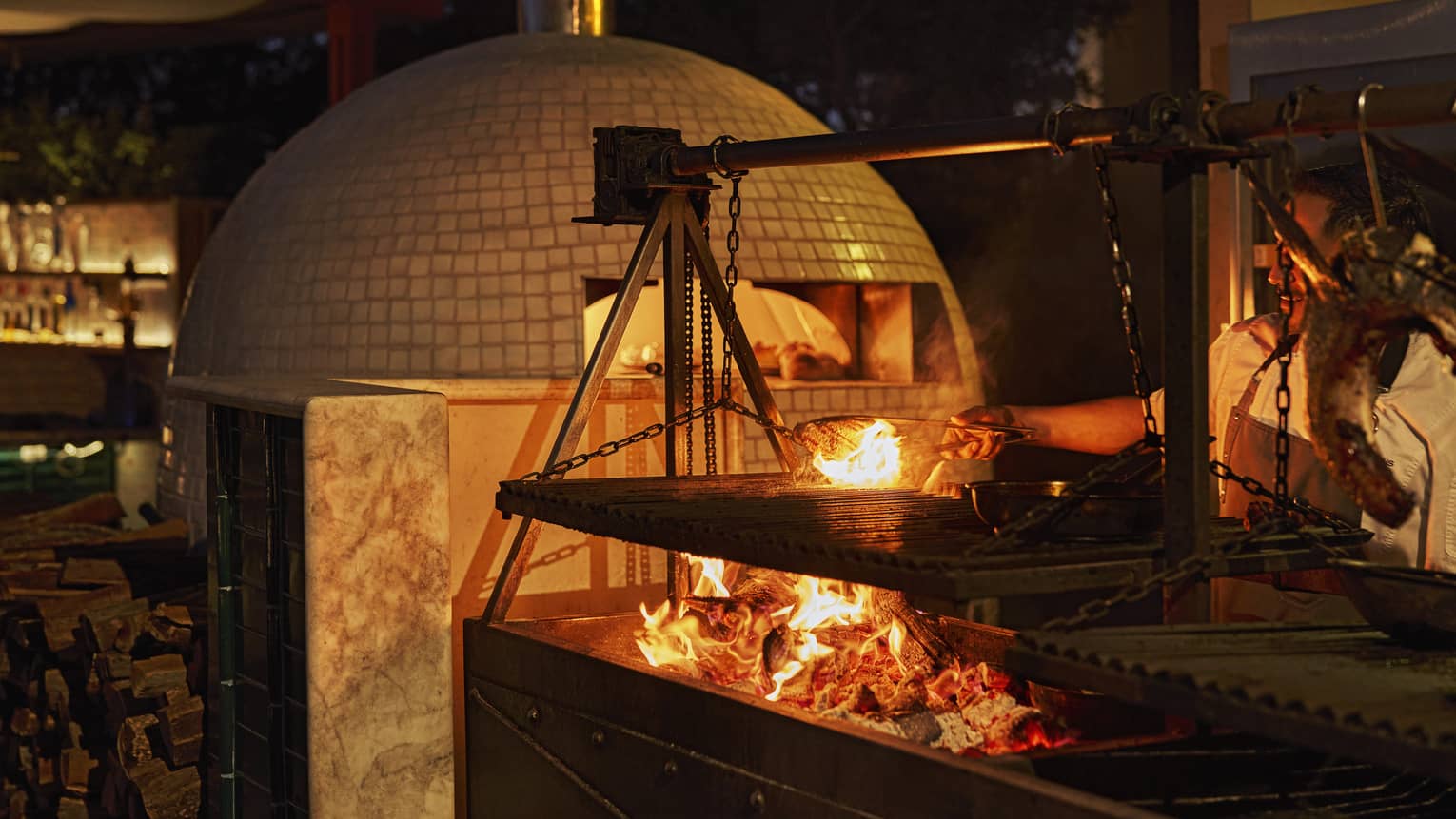 Wood-fired pizza oven and open fire in outdoor kitchen