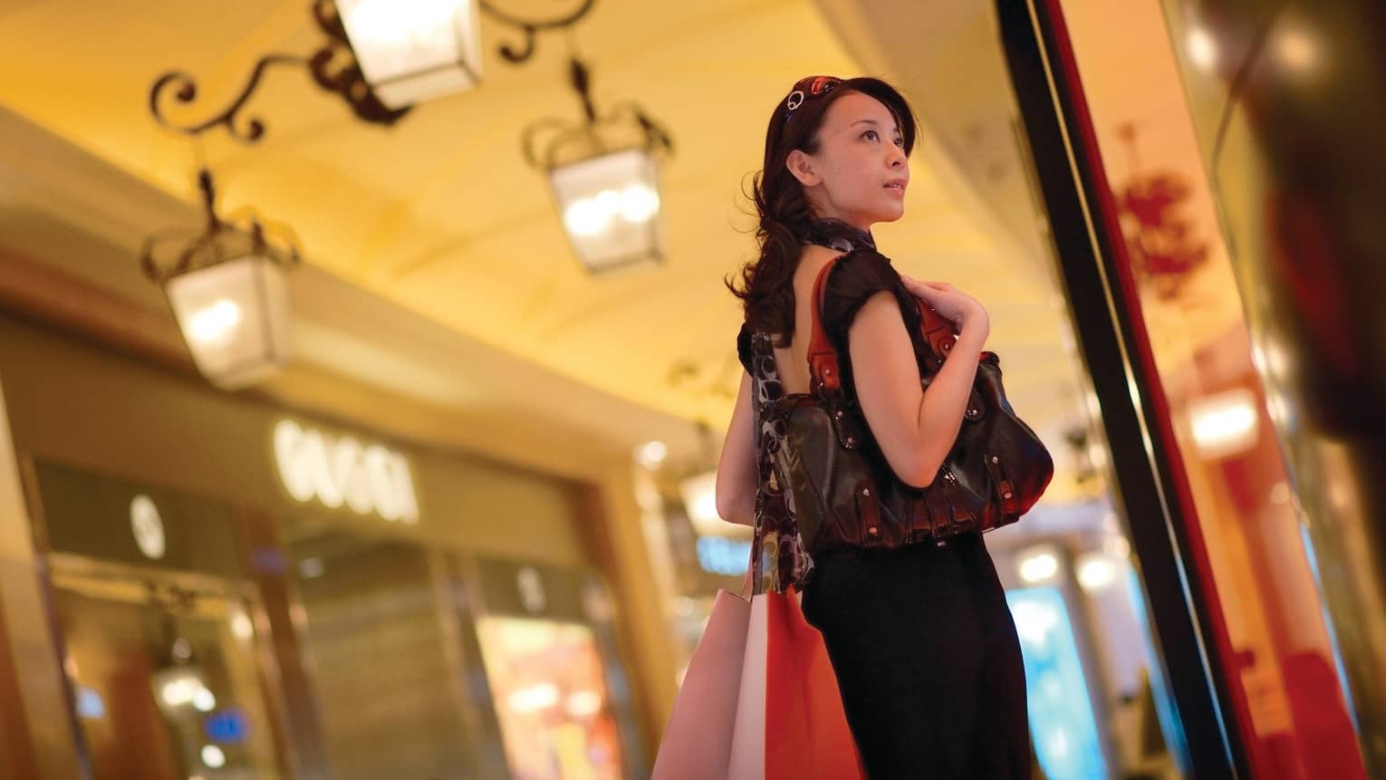 Fashionably-dressed woman carrying bags, designer purse in shopping mall