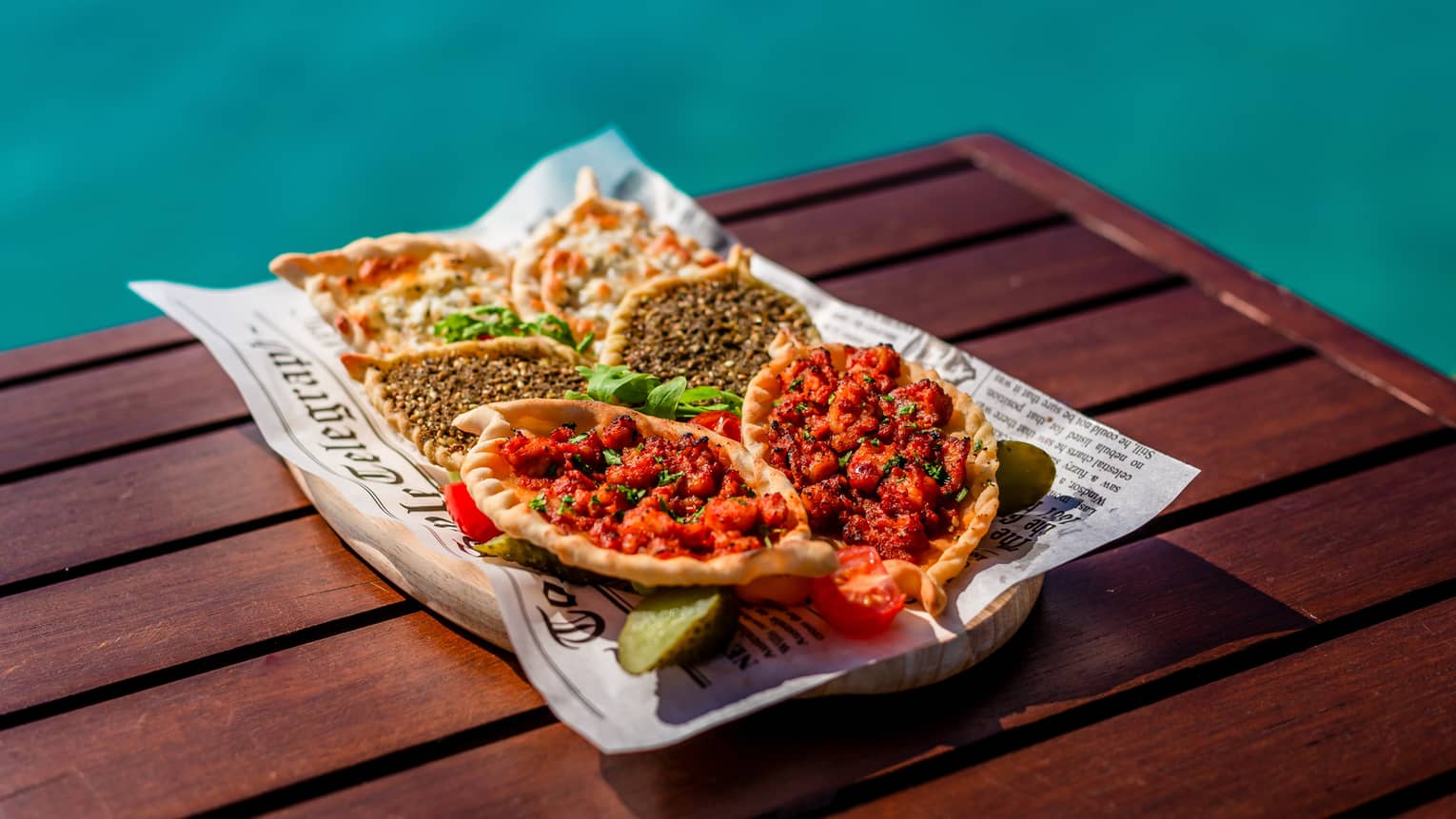 Manakish selection with levant pastry and various toppings on poolside table