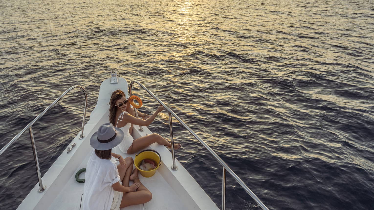 Two women enjoy snacks at the helm of a private yacht at sunset