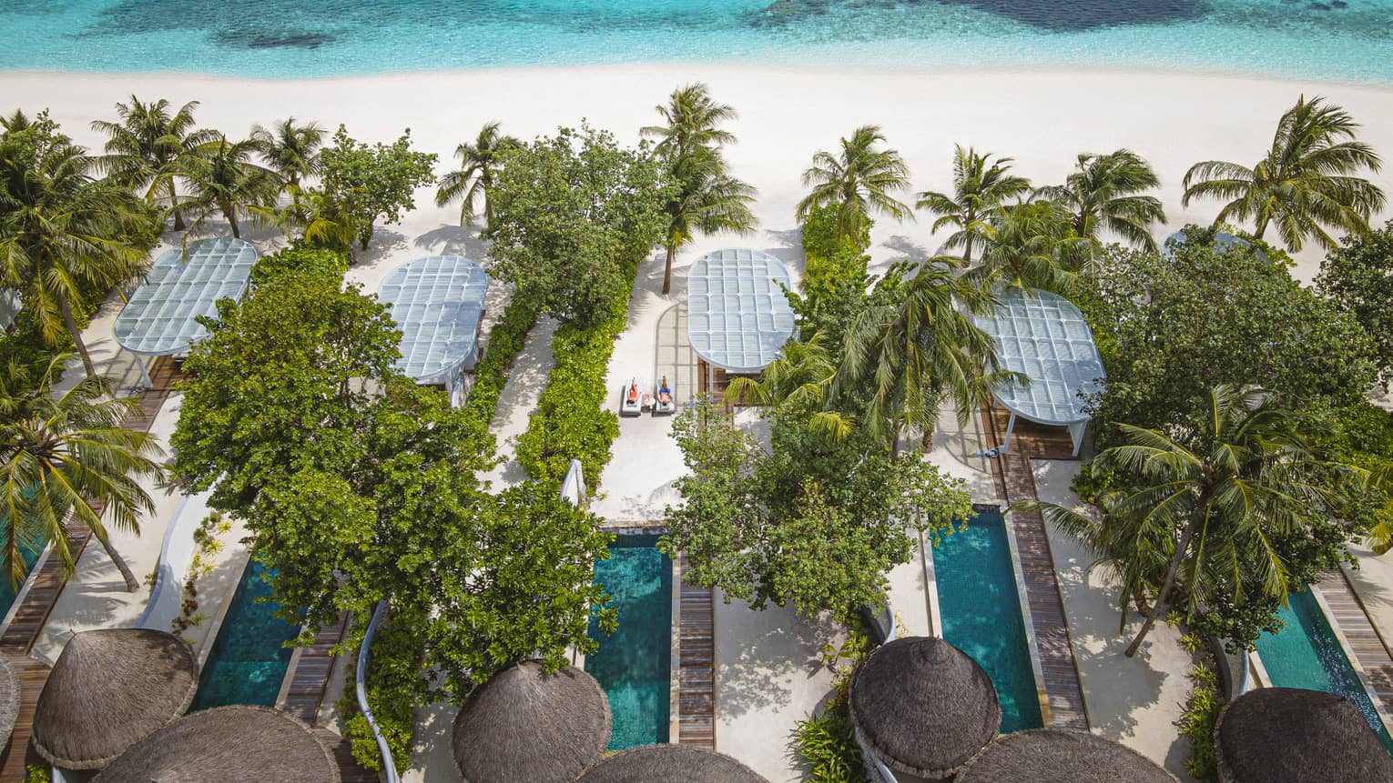 Aerial view of beachfront villas with pools at luxury tropical resort