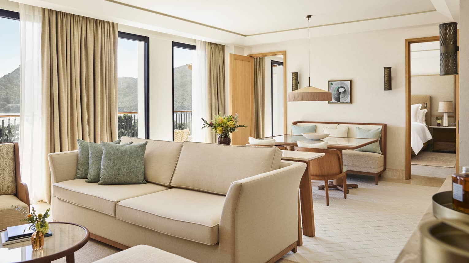 Interior of a contemporary suite at a resort, featuring a living and dining area with cream and light-blue decor