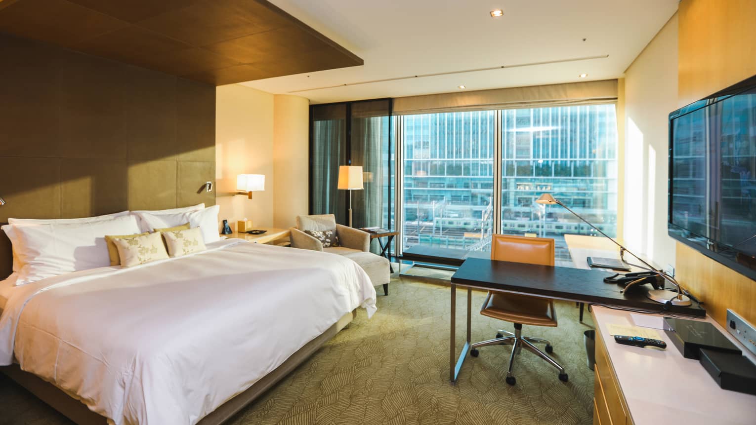 Deluxe City-View Room bed, armchair across from desk, TV