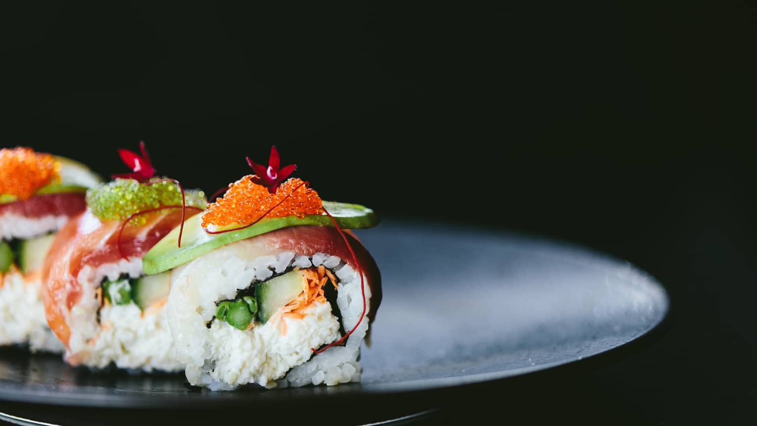 Sushi roll with avocado and roe topping