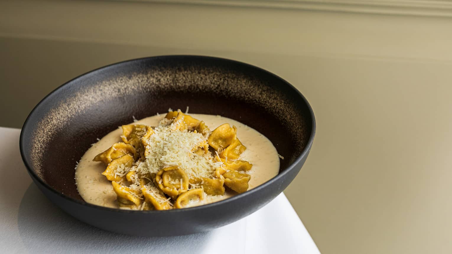 Pasta in a bowl with sauce poured on it.
