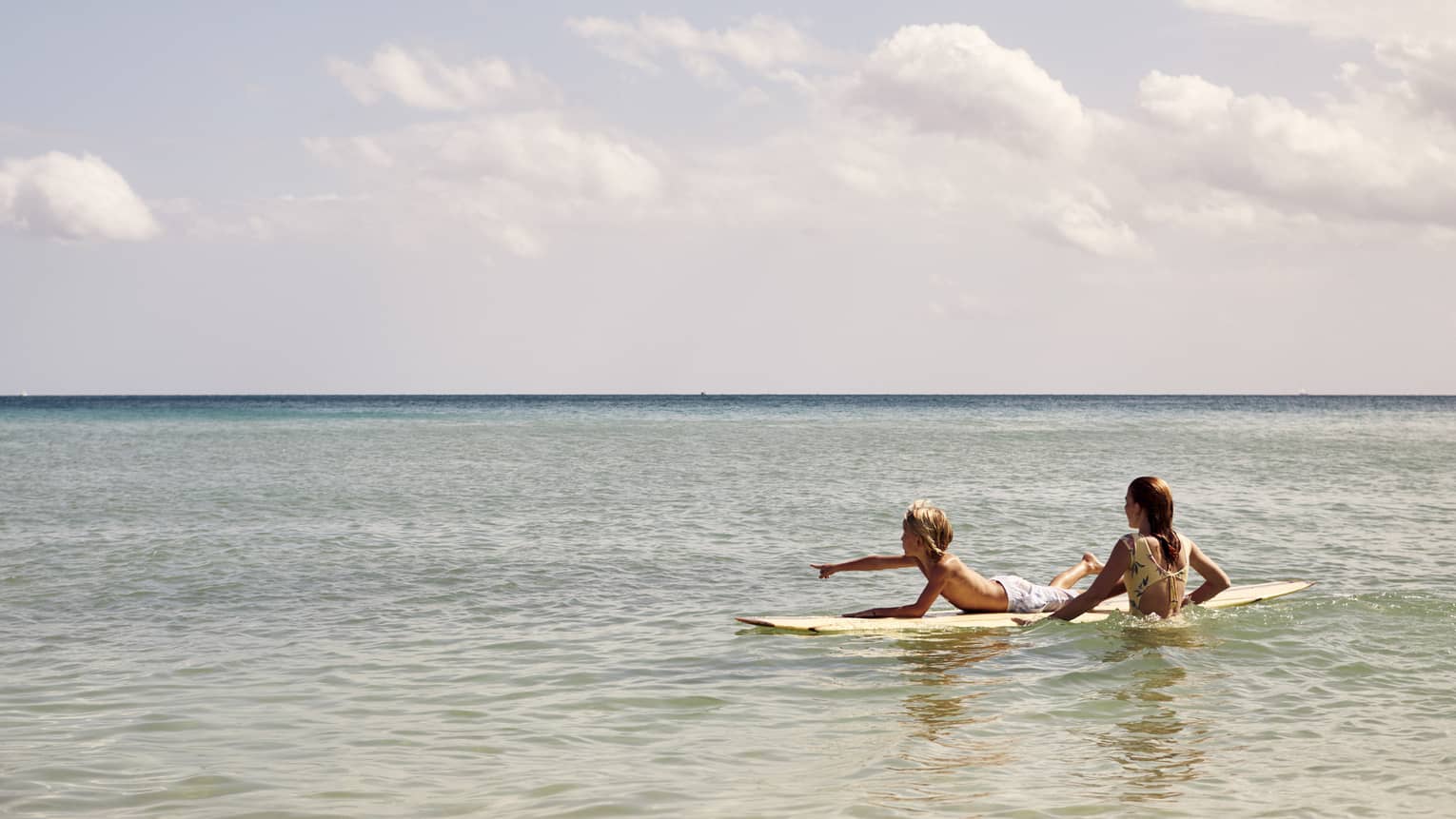 Two guests surfing in the ocean.