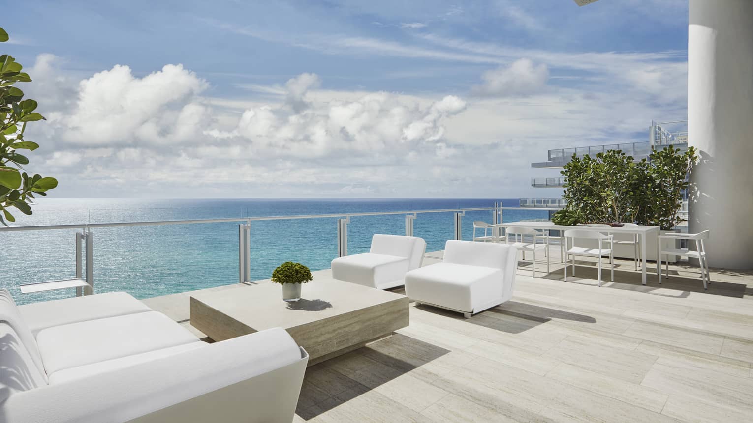 Modern white patio sofas, table on large, sunny deck overlooking blue ocean at Four Seasons Hotel at the Surf Club, Surfside, providing luxury vacation rentals in Miami.