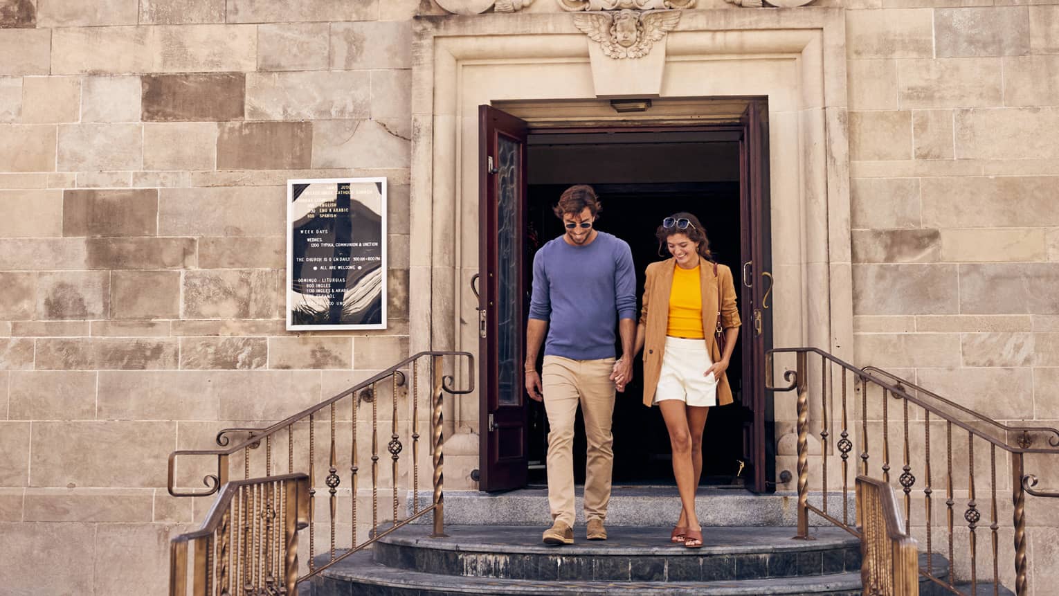 A man and woman walking out of an old stone building.