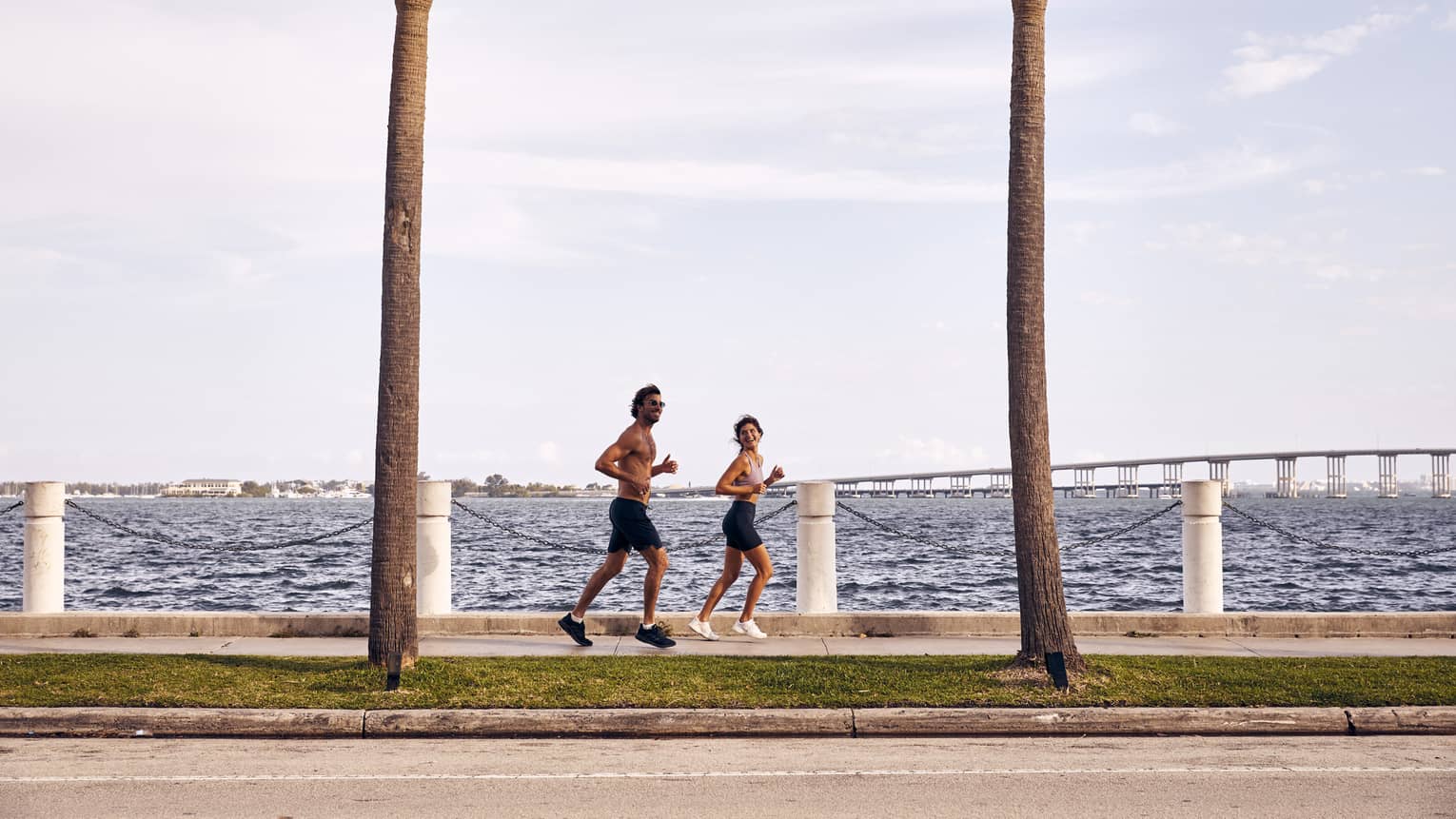 Man and woman running on sidewalk next to water