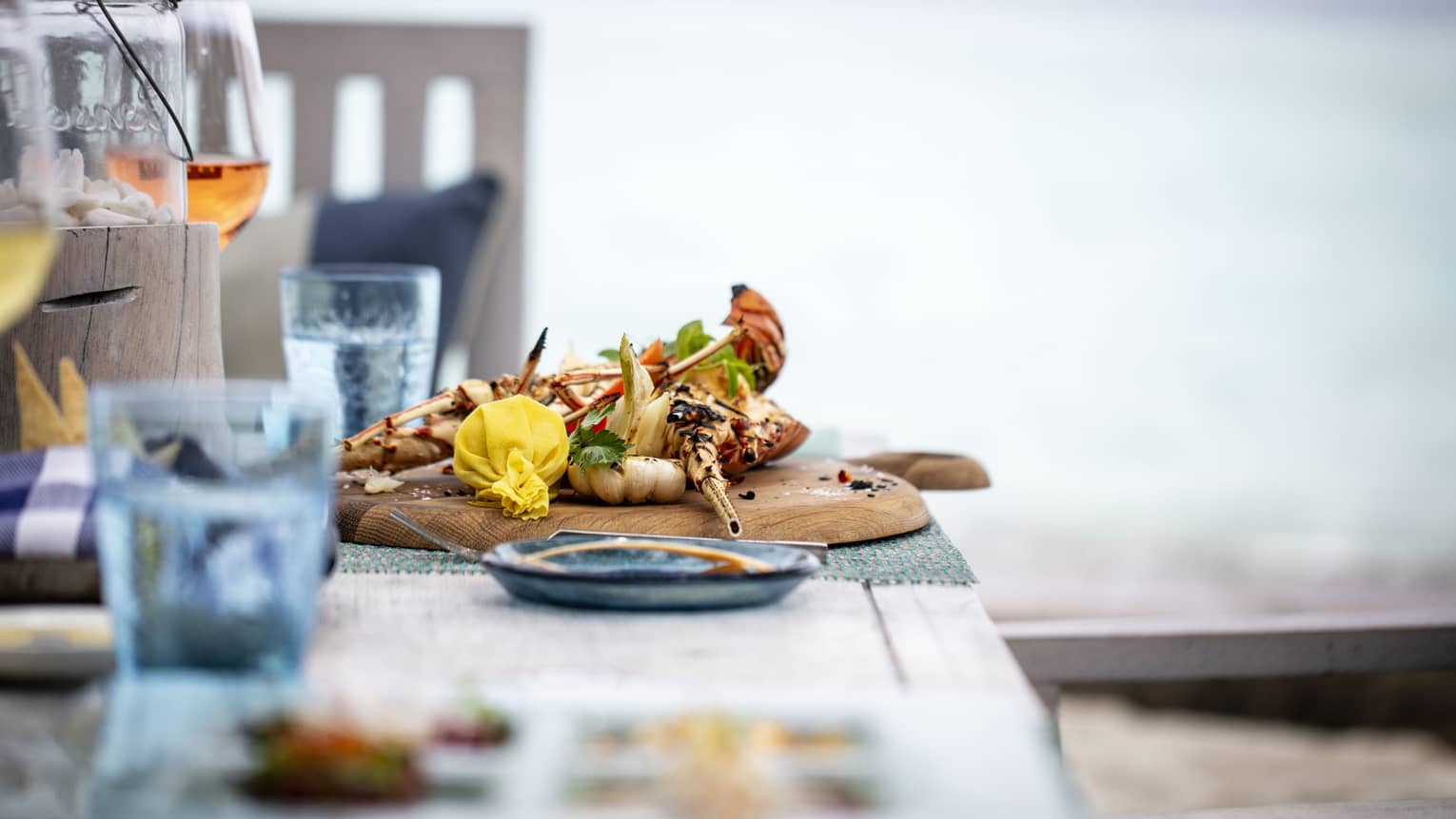 A tastefully set table with a glass of rose and a chicken dish overlooking the ocean at Fuego Grill