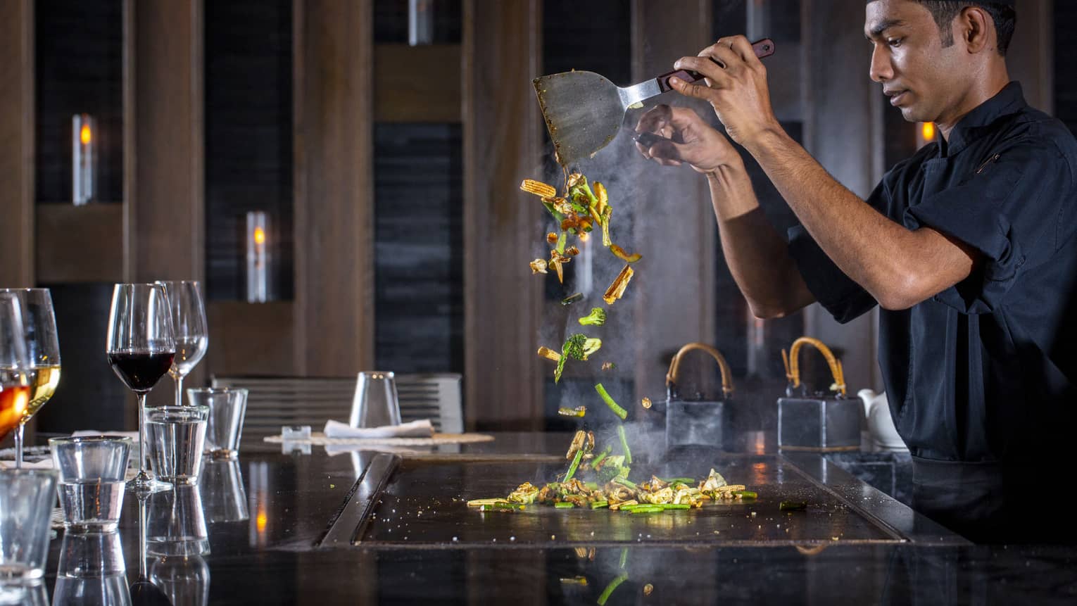  A four seasons dining staff working on a towering dish made of vegetables at the bar