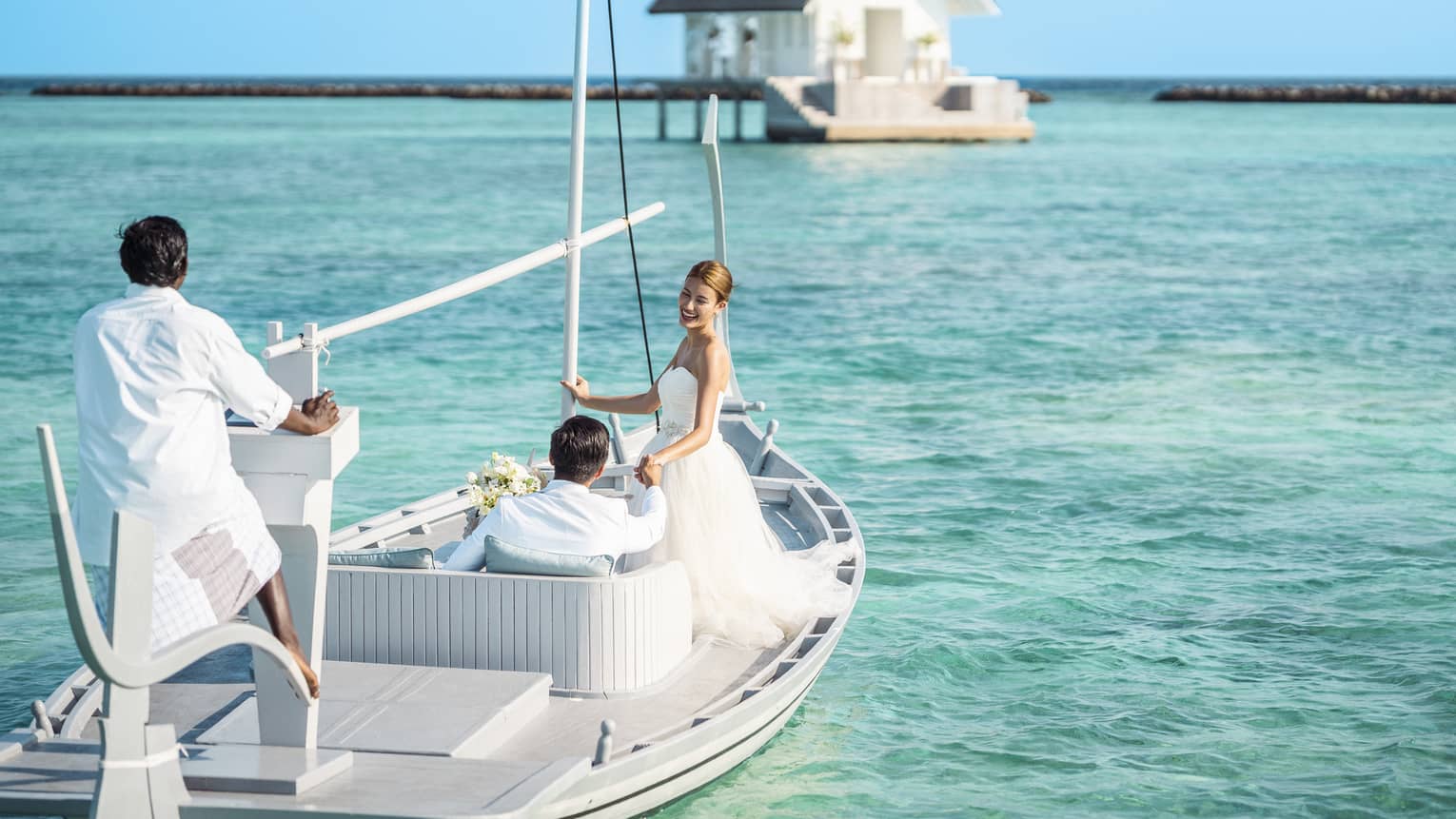 Bride and groom head toward their overwater wedding venue in traditional Maldivian boat