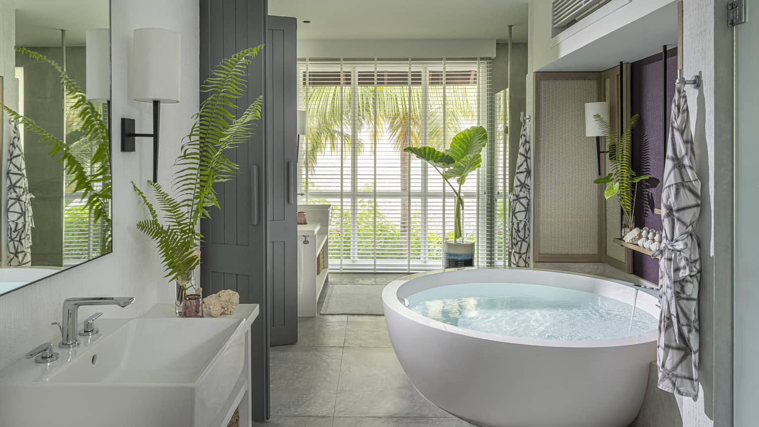 Luxury resort bathroom with free-standing circular tub and garden window view