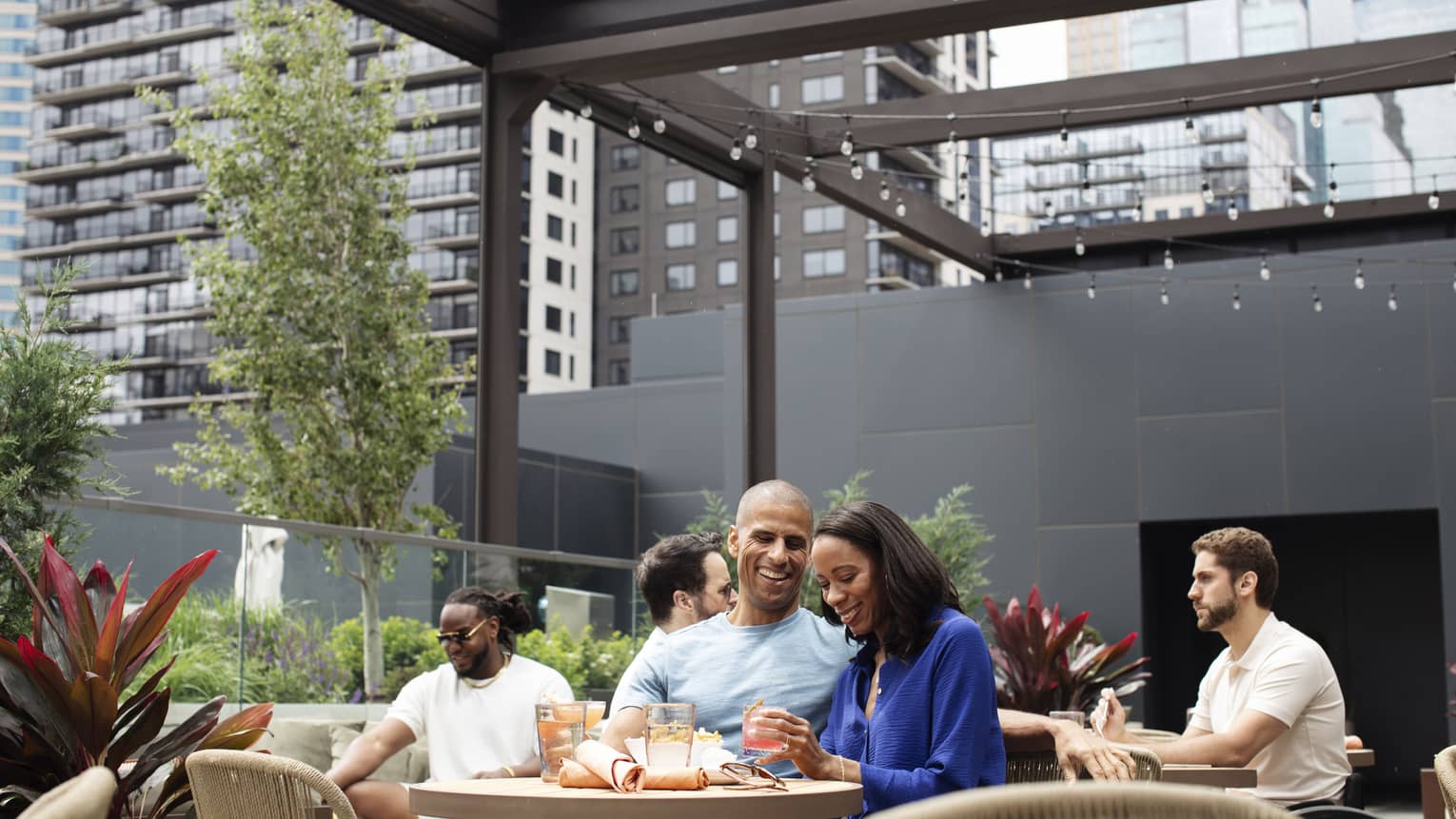 Guests sitting at dining tables at an outdoor terrace with lights along the open ceiling.