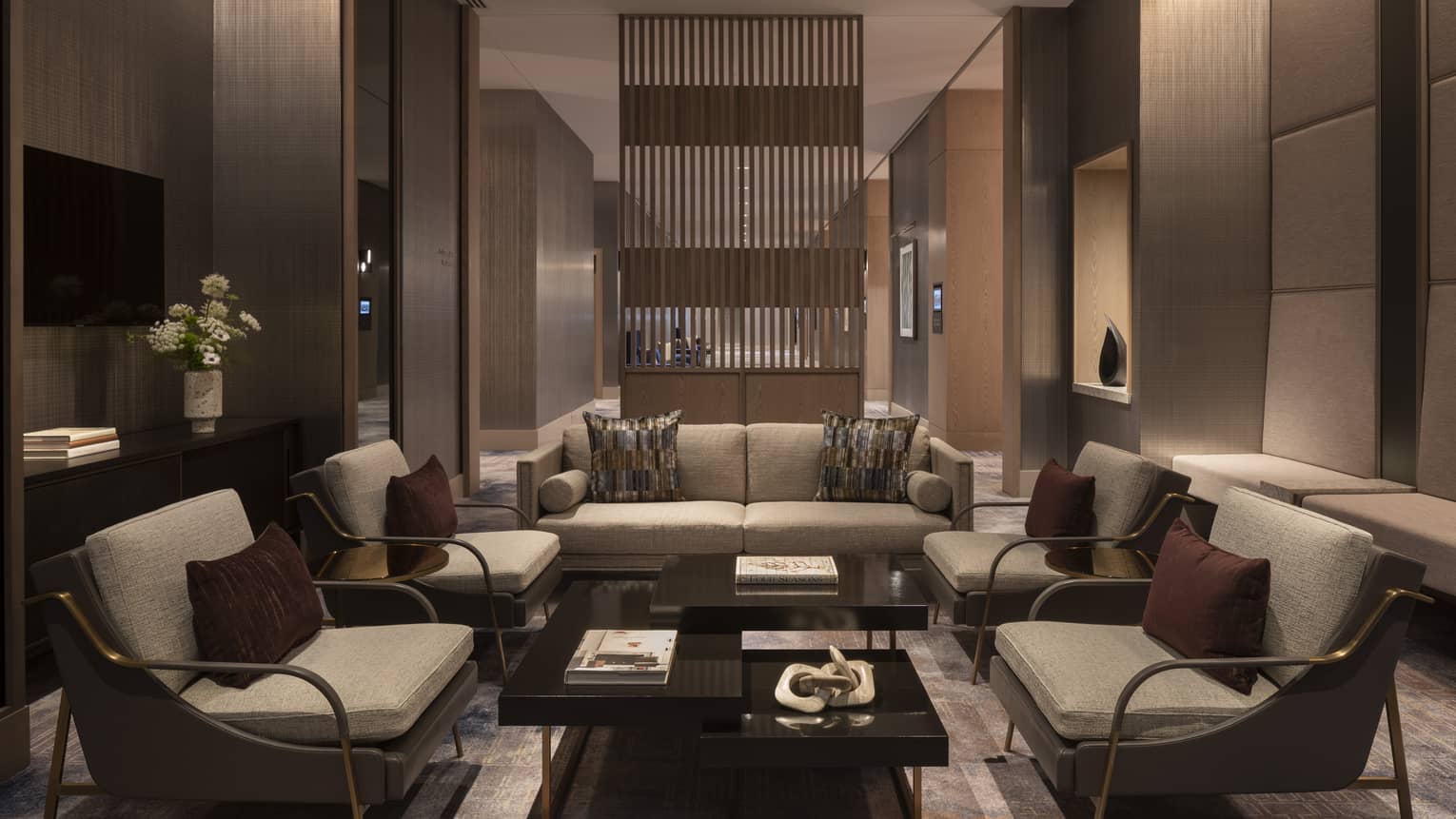 A dimly lit sitting area with a coffee table, chairs, and sofa.