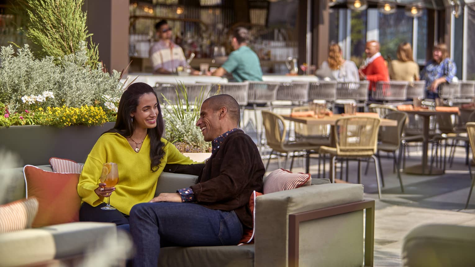 Woman in yellow shirt sitting beside man in brown shirt, both laughing.