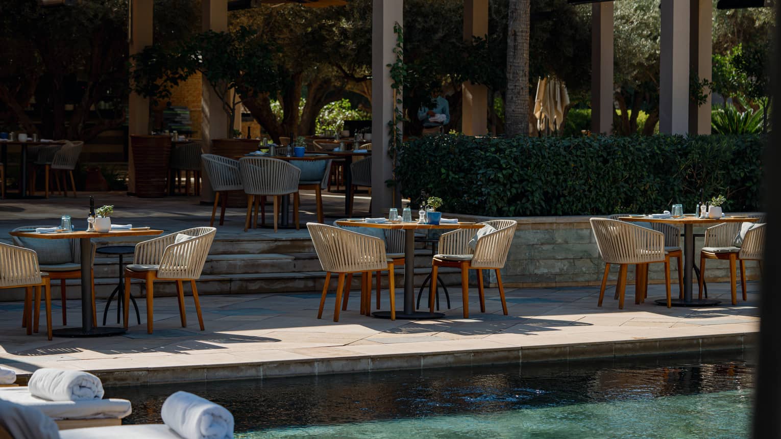 Round tables on tiered poolside deck restaurant