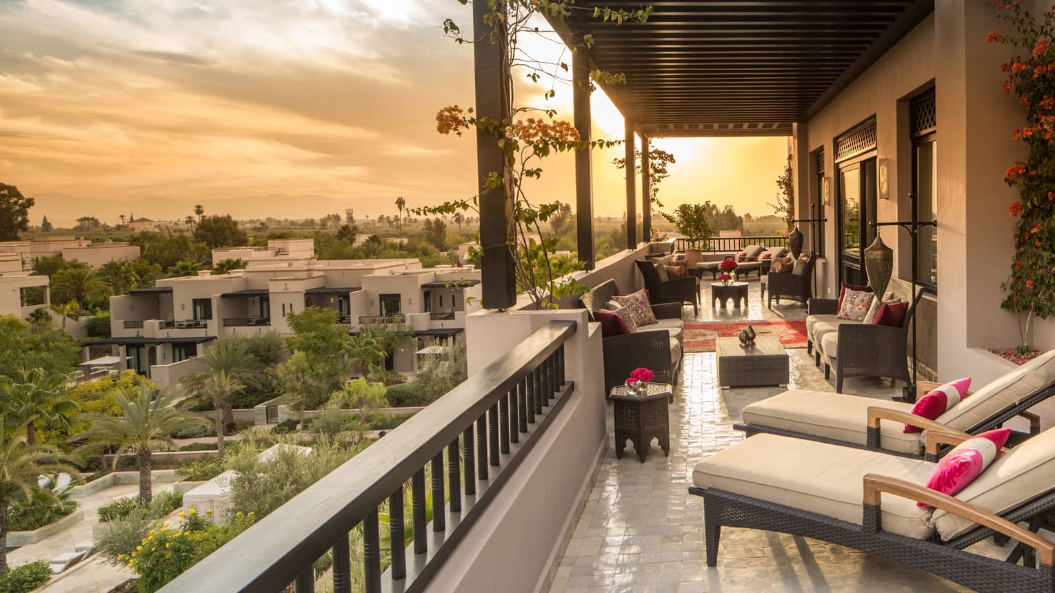 Moorish gardens below below long white hotel balcony with plush patio furniture 