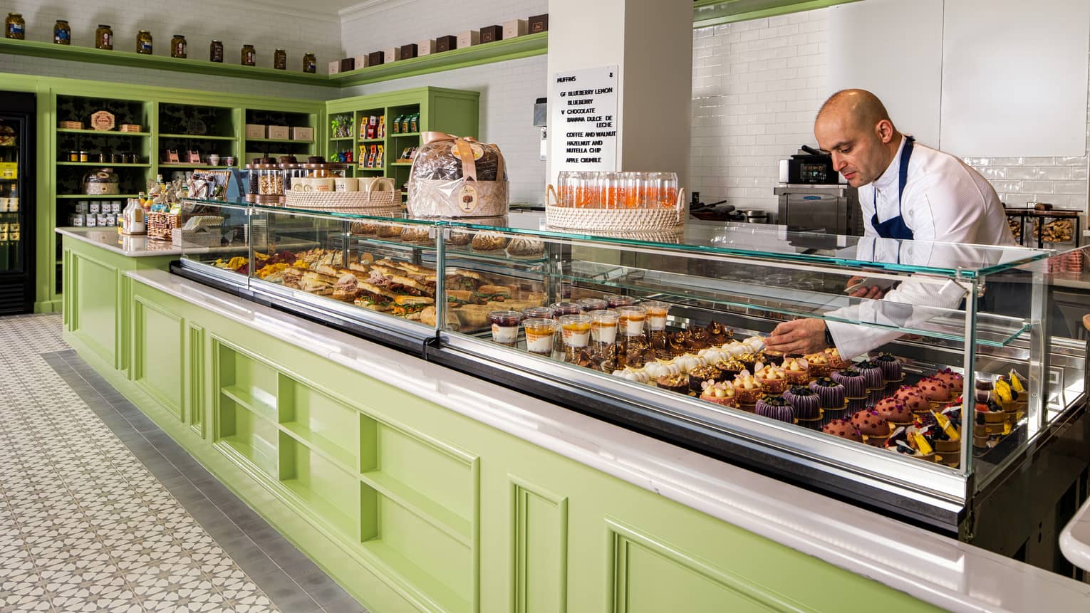 Deli counter with a glass case on top of lime green cabinetry and tiles floors