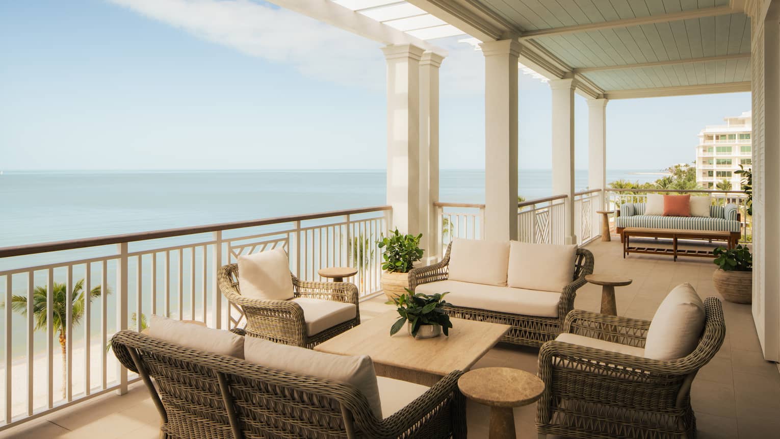 A luxury resort suite covered balcony with lounge furniture and ocean view