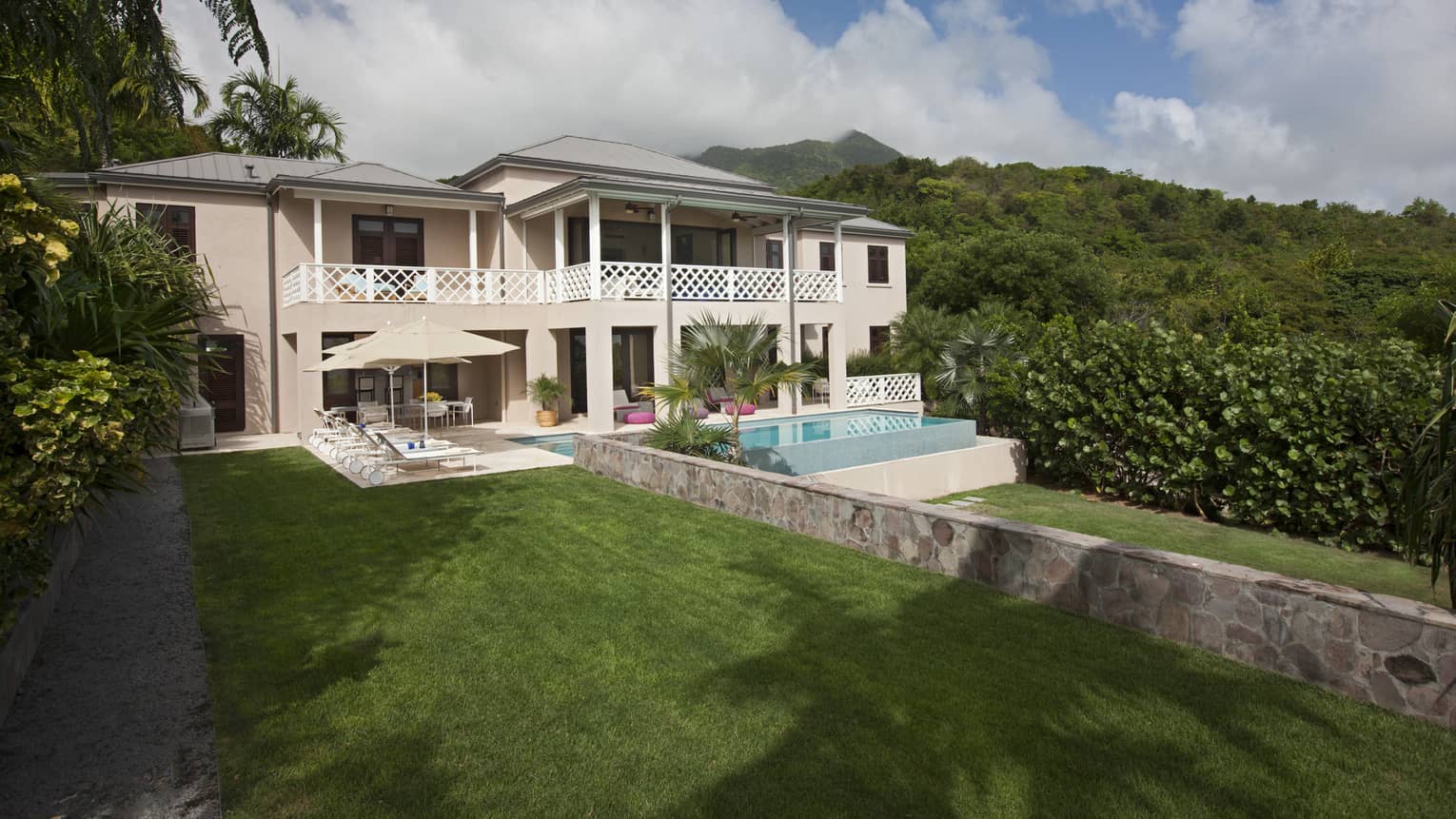 Two storey white villa and plunge pool surrounded by lush greenery