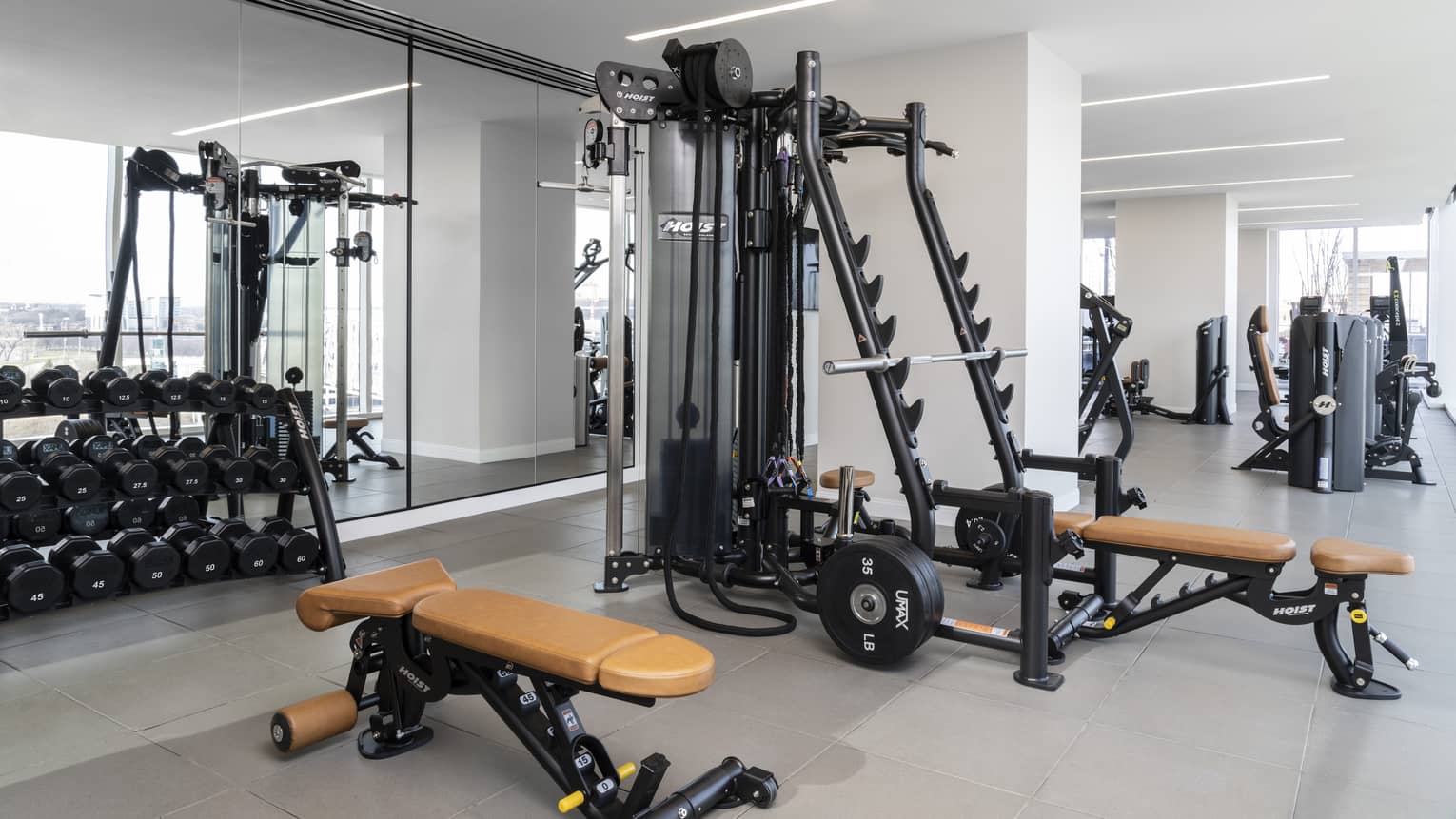 Fitness equipment in a gym with weights and a mirror.