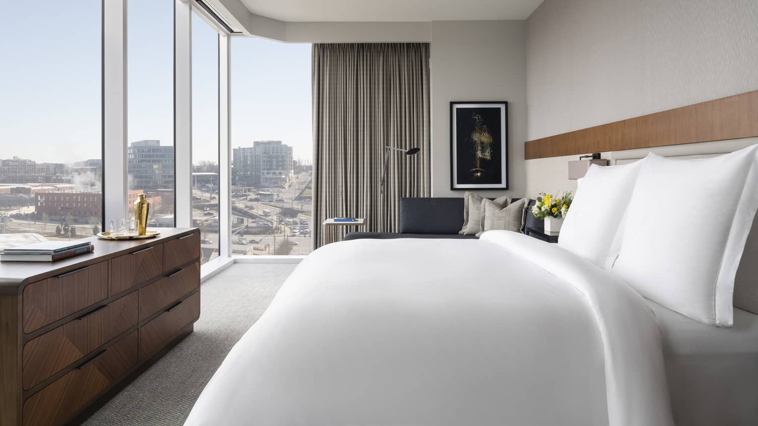 Hotel room with king bed looking out to corner-view wall of windows