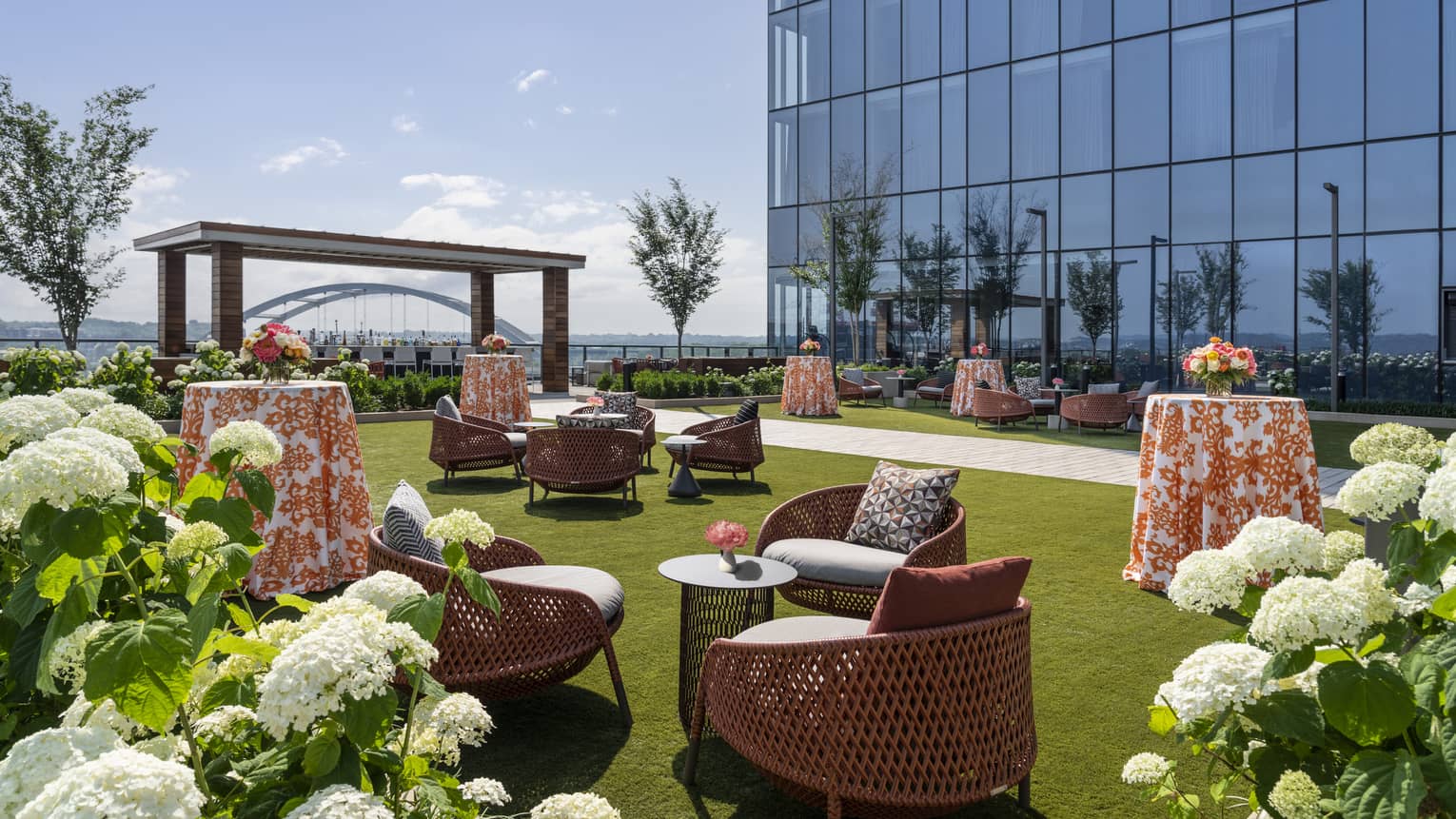 Lawn with chairs and tables and plants with white flowers.