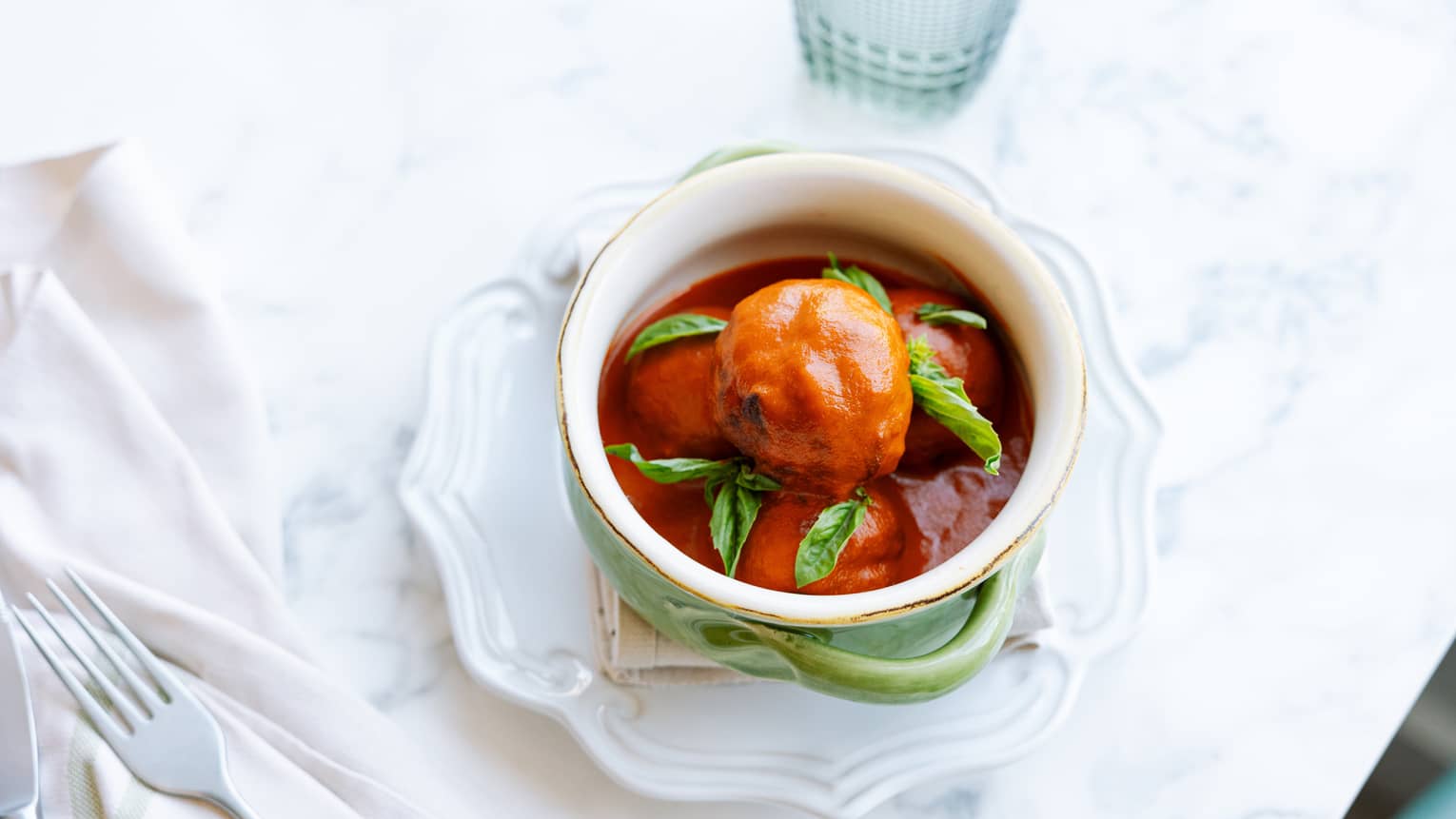 Meatball and a spicy sauce in a white bowl.