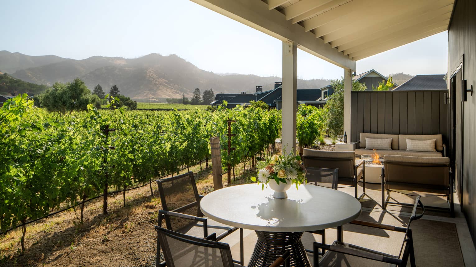 Private, covered patio of a resort suite located next to lush vineyard