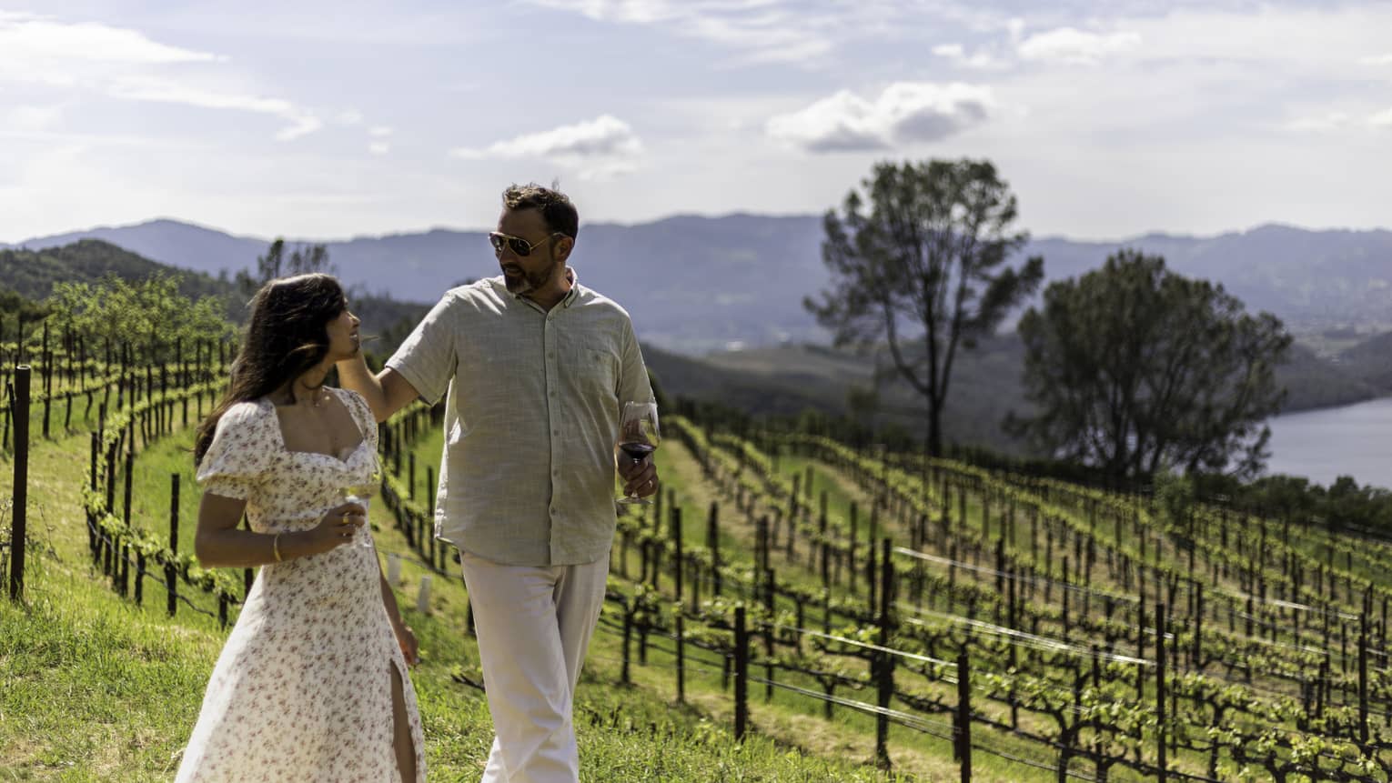 Two guests walking through a vineyard with the mountains in the background.