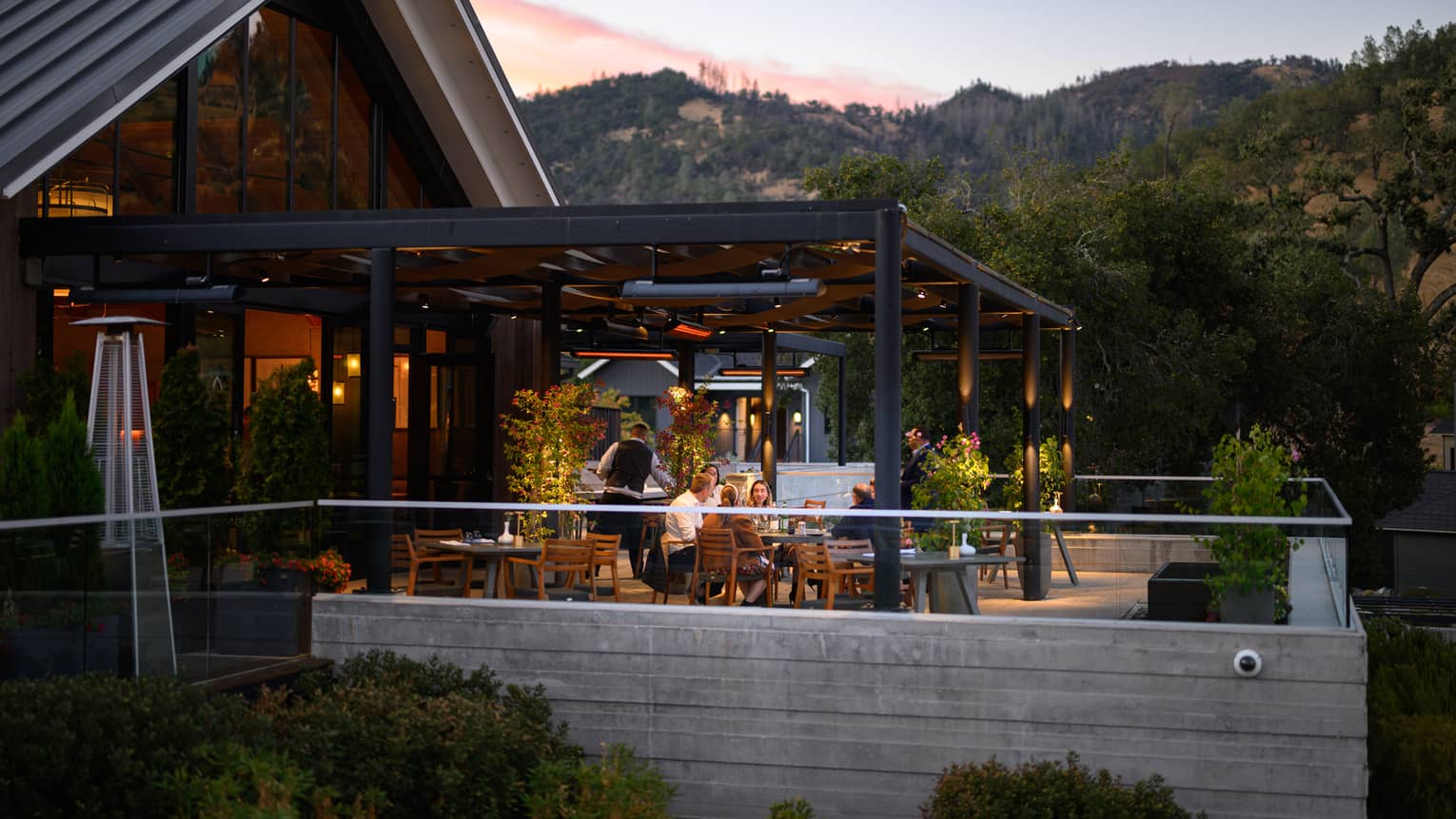 An outdoor terrace with soft lighting and guests dining at the tables
