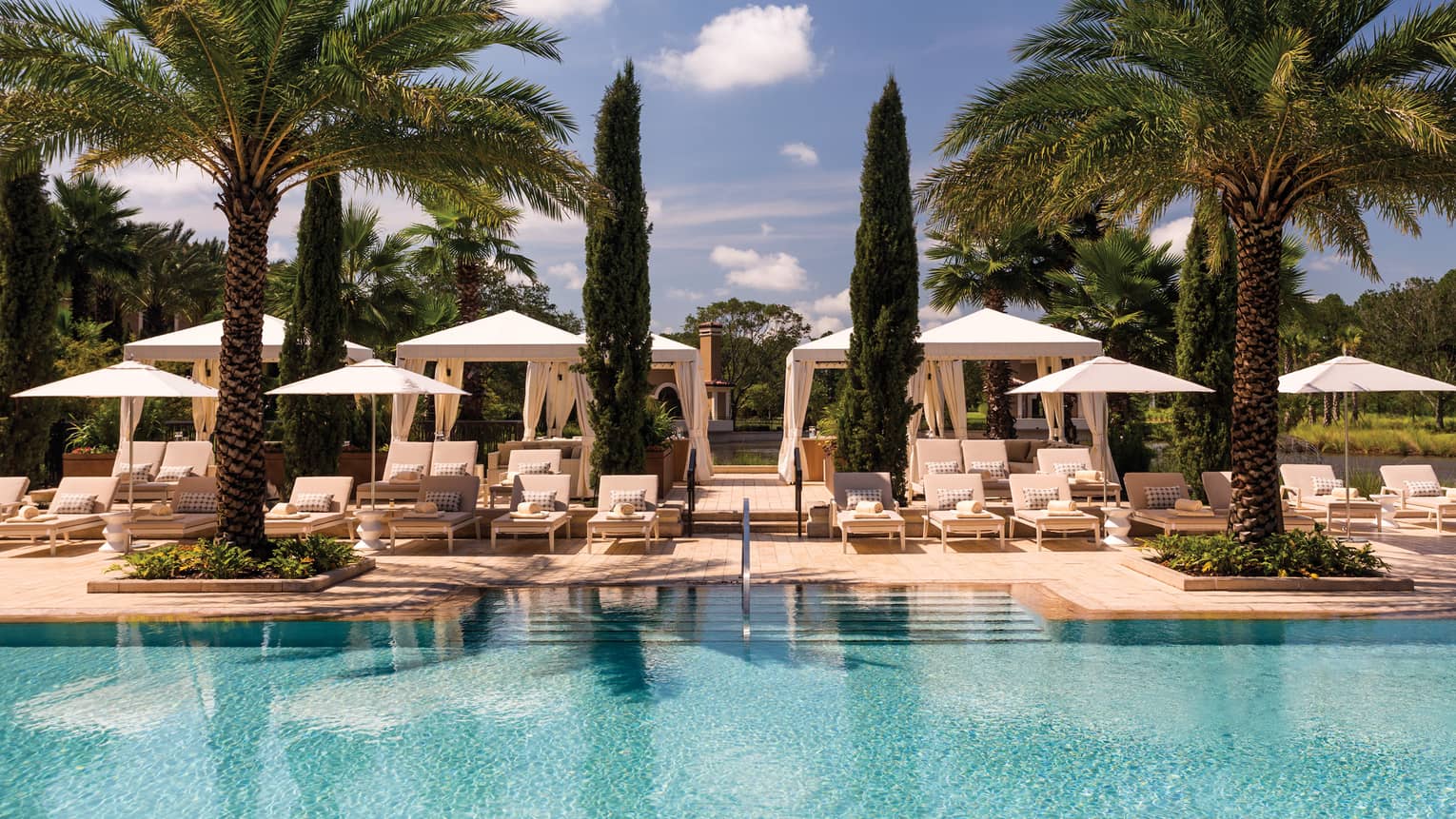 Pool with palm trees, lounge chairs and umbrellas