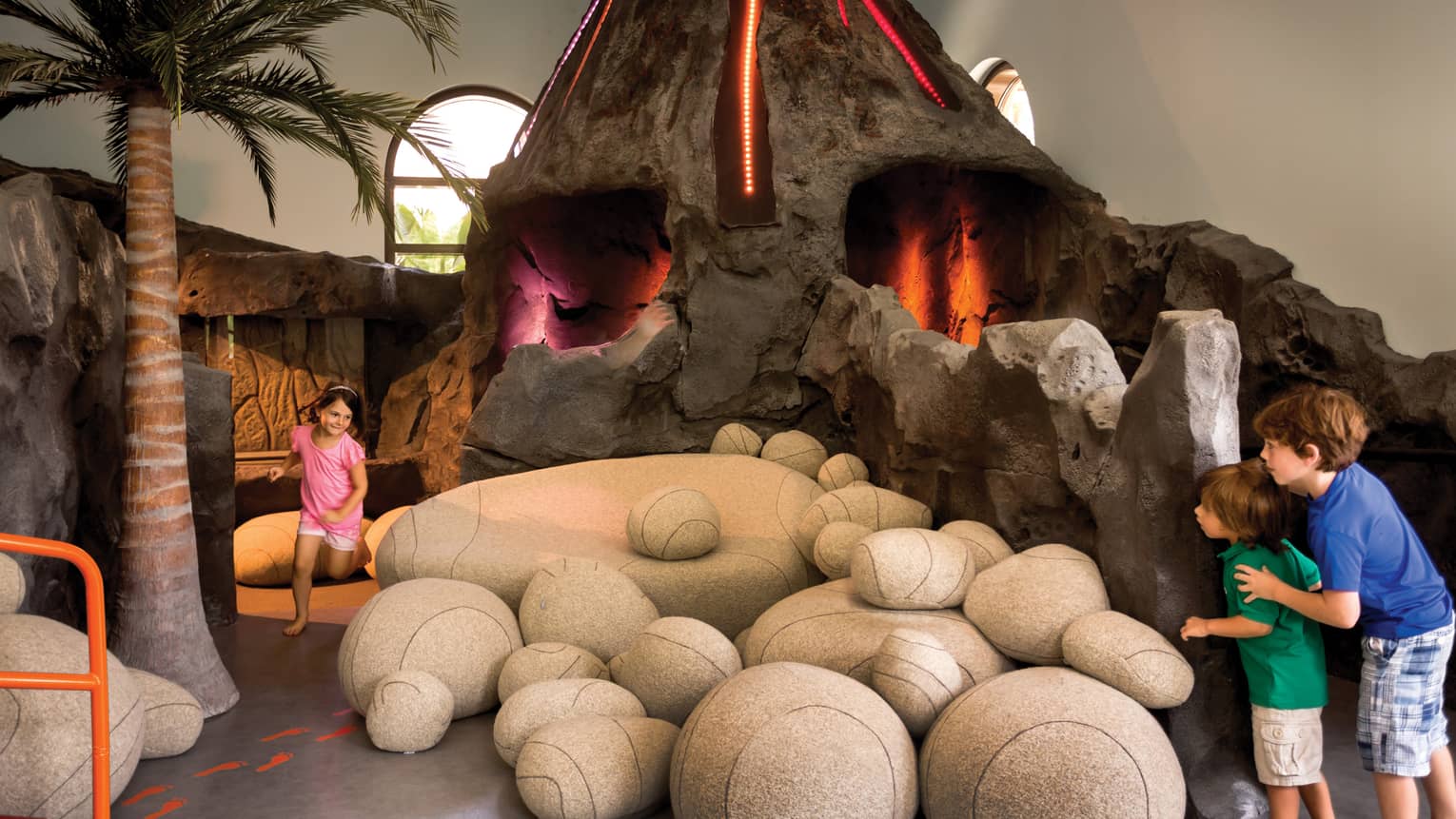Kids run around large interactive volcano play structure in Kids Playzone