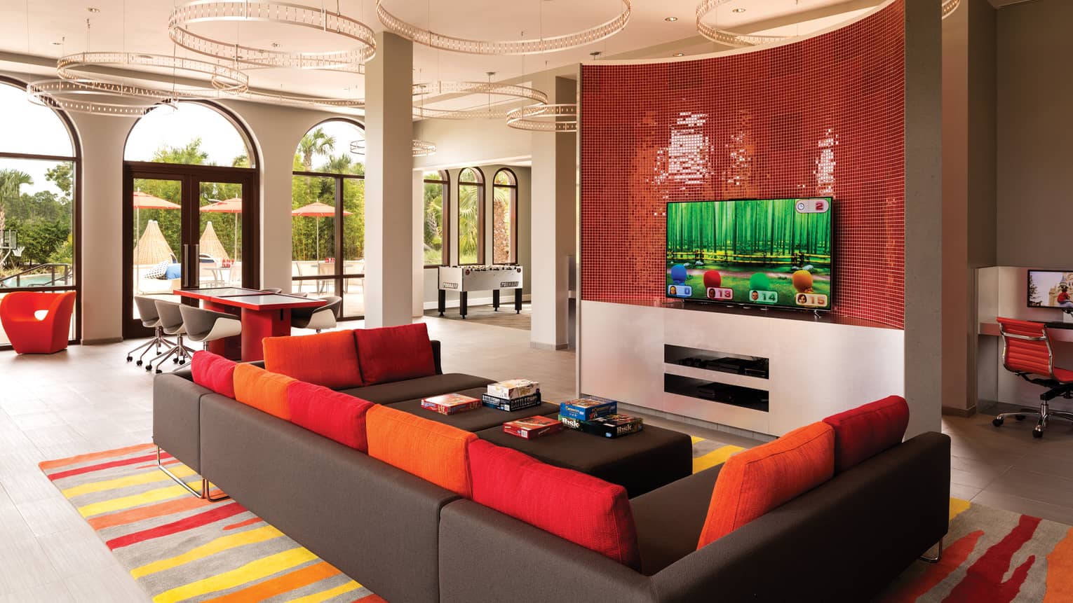 Game room with a red and black couch and television on the wall.