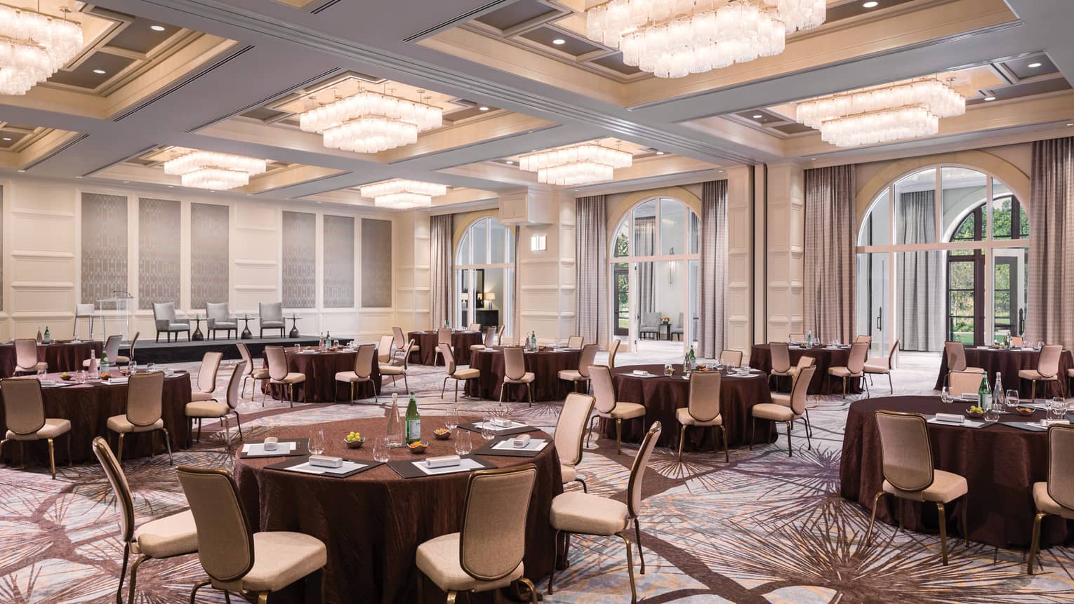 The Palm Ballroom meeting event with round tables under rows of tiered chandeliers 
