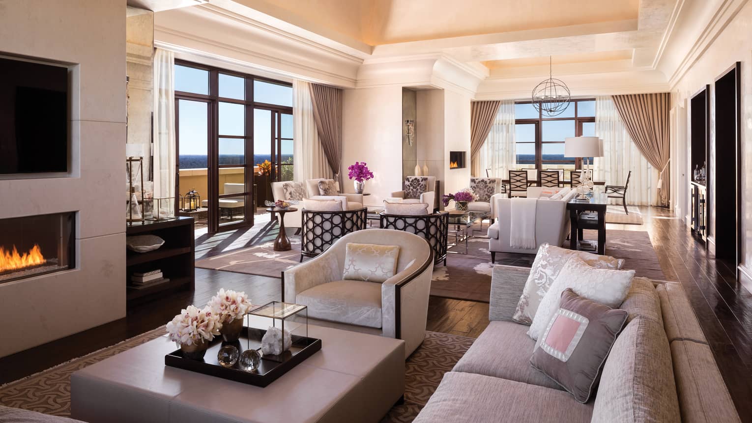 Presidential Suite sofa, armchair, large ottoman table by gas fireplace, TV in front of dining room