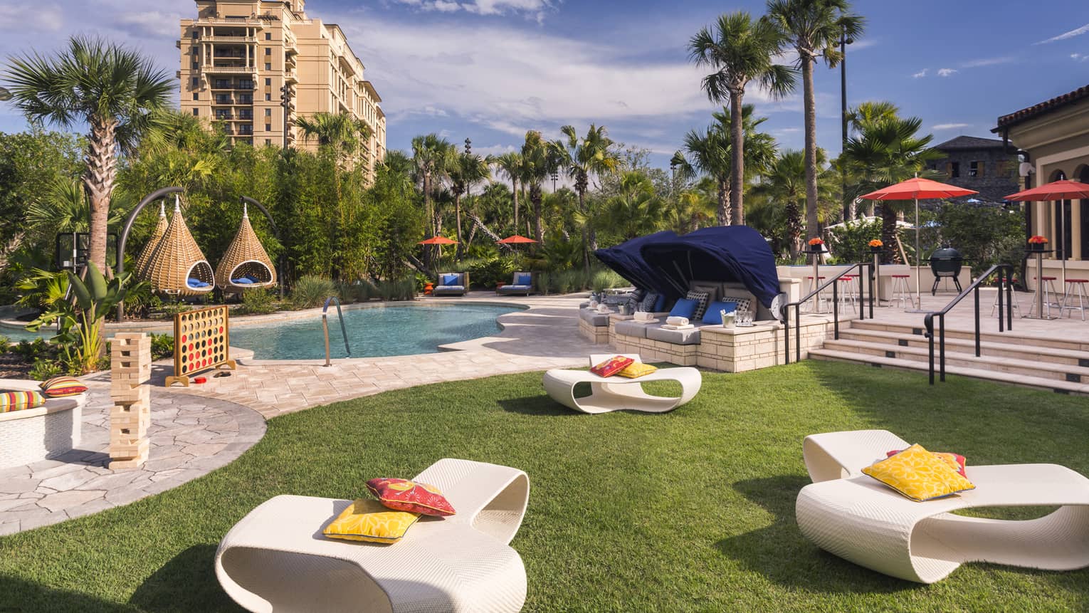 White patio chairs, hanging baskets, palm trees around swimming pool deck