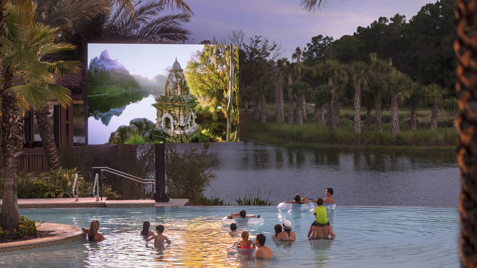 Under a dusk grey sky, adults and children watch a large outdoor screen while wading in a pool bordered by palm trees.