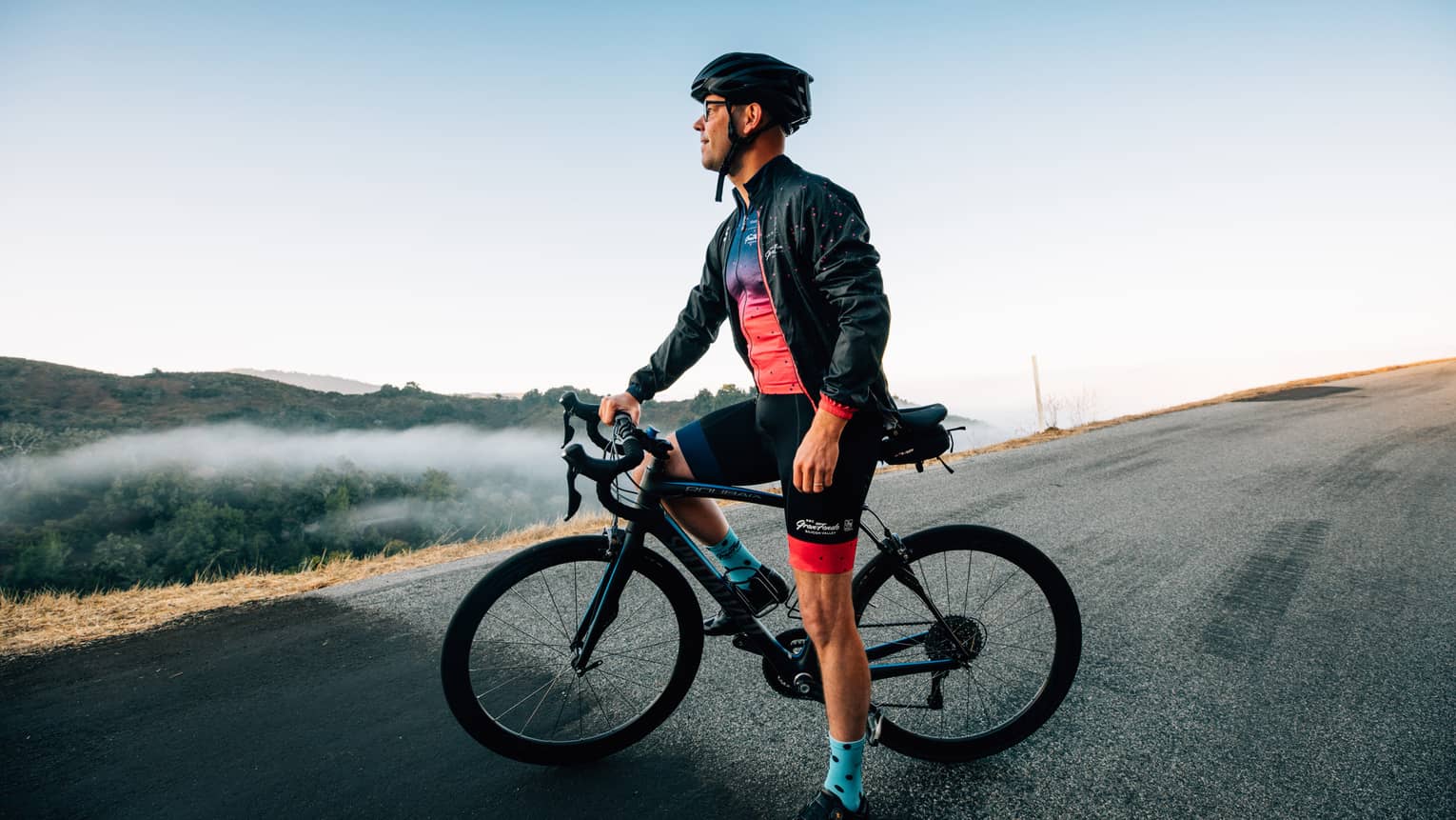 A male cyclist pauses to take in the mountainous surroundings.