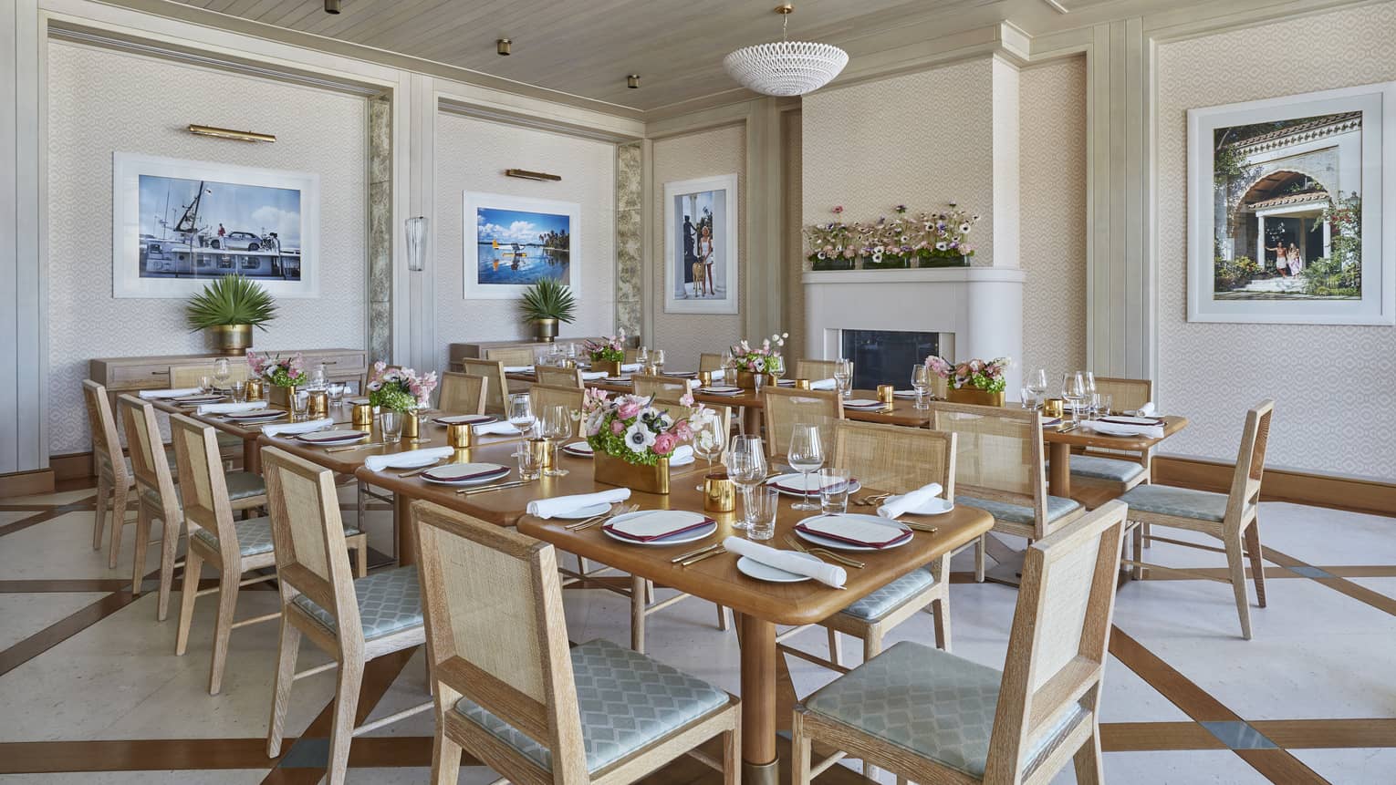 Bright private dining room with two long tables, framed photos and fireplace along walls