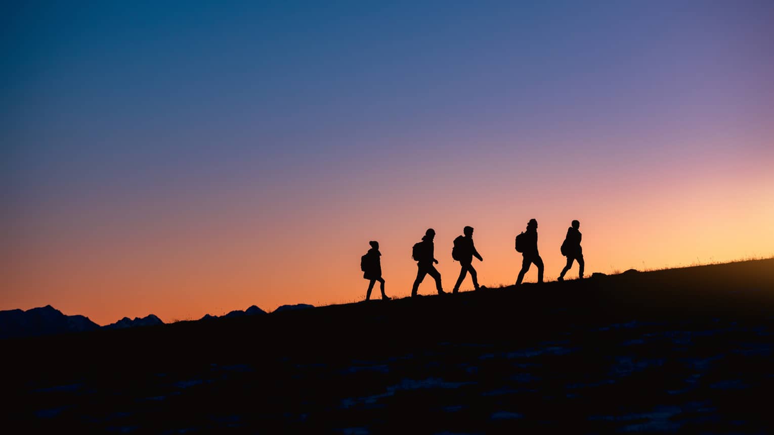Group hikes on ridge at sunset