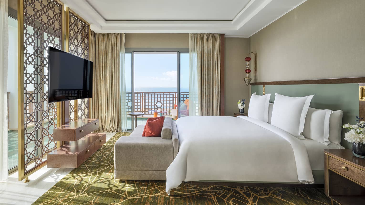 Luxury hotel suite bedroom with king bed, chaise, wrap-around sea-view balcony and TV at Four Seasons Hotel Rabat